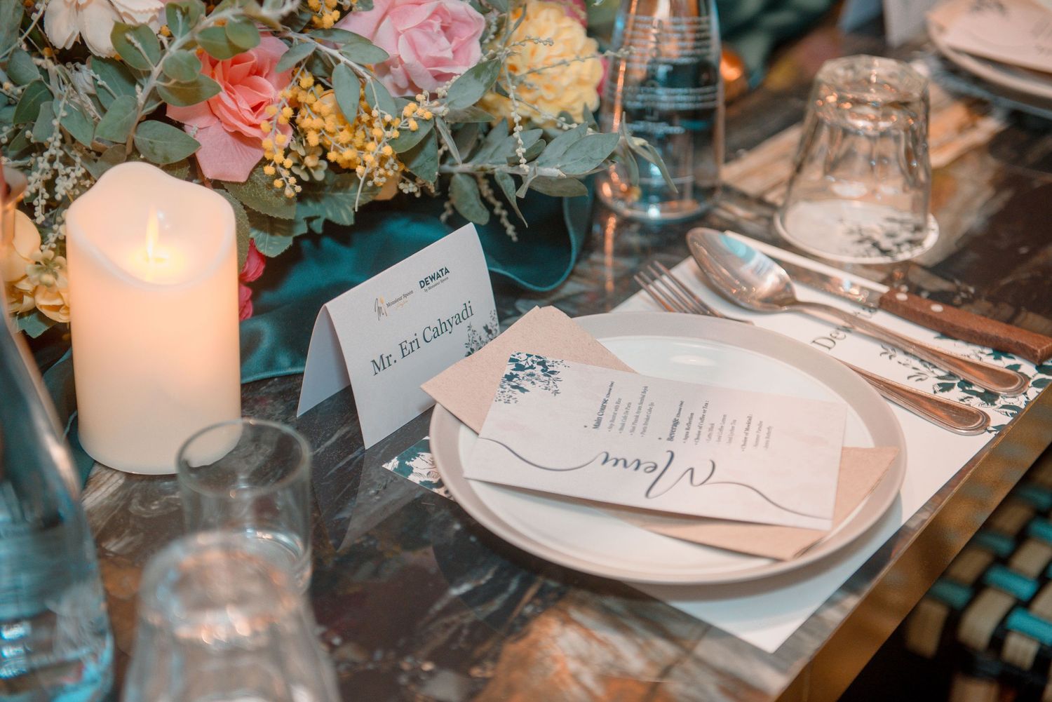 Elegant wedding reception table settings with soft candlelight, pink flowers, and delicate place cards create a romantic ambiance.