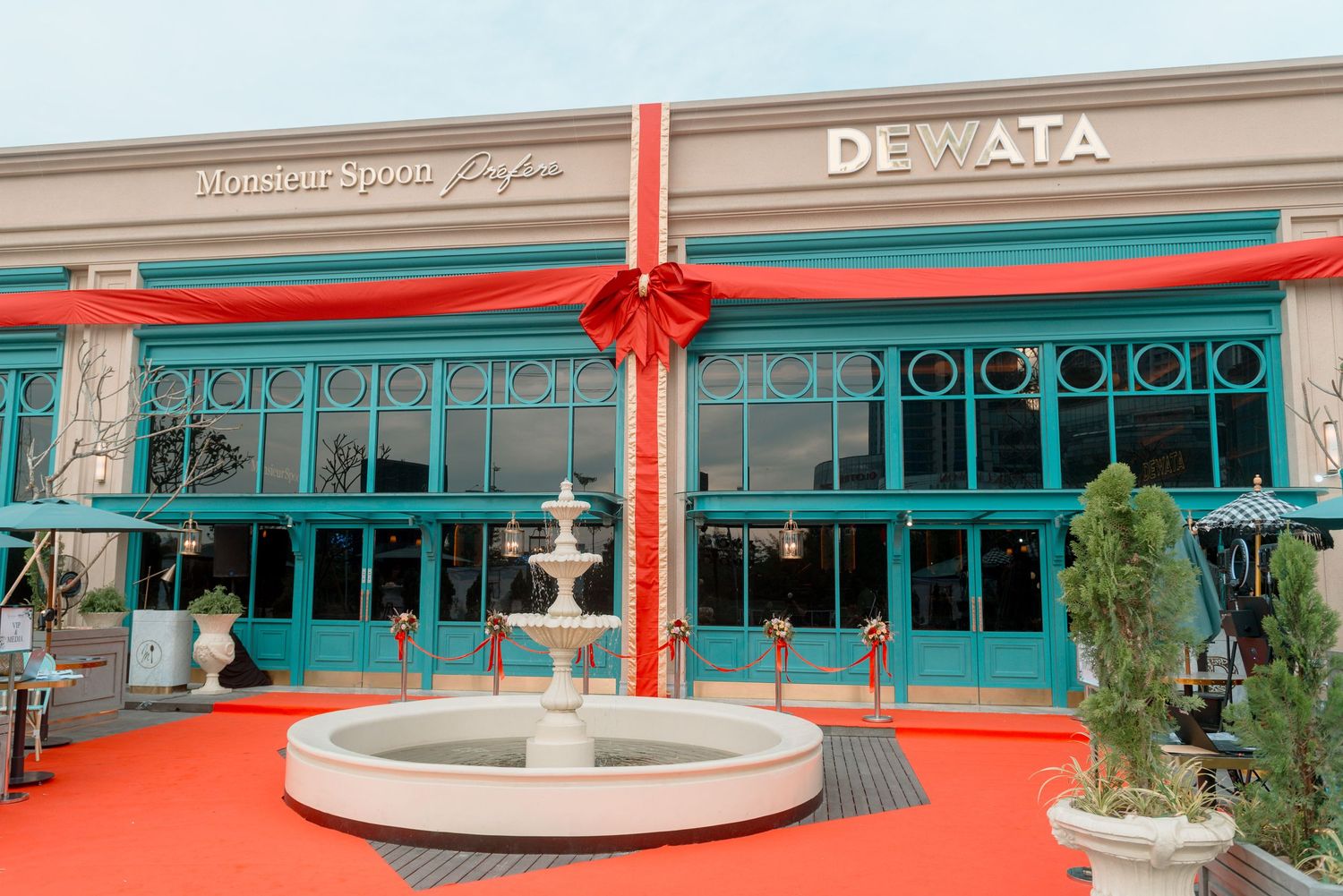 A series of retail storefronts with glass windows and signage showing a shopping mall or commercial strip exterior.