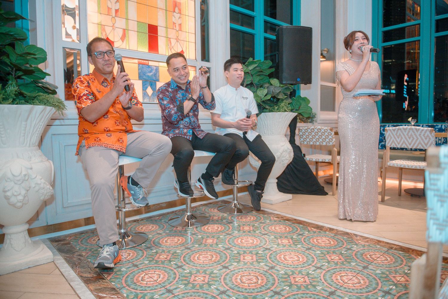 Group gathering in a modern indoor space with teal-colored walls and patterned carpeting.