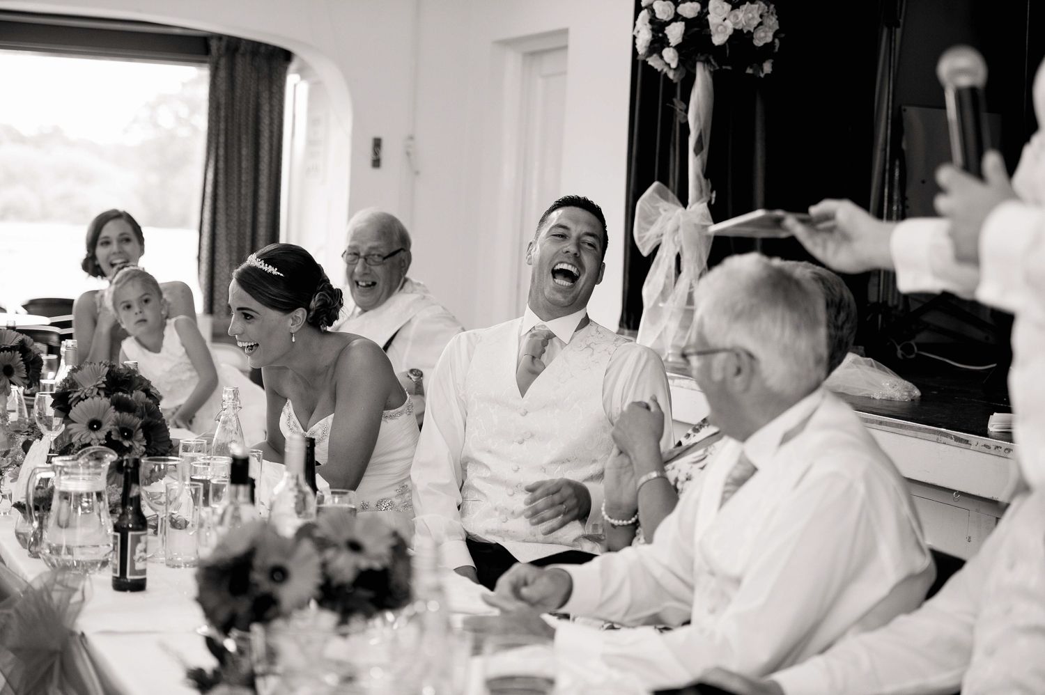 A group of people enjoying a lively social gathering at a dining table with drinks and laughter.