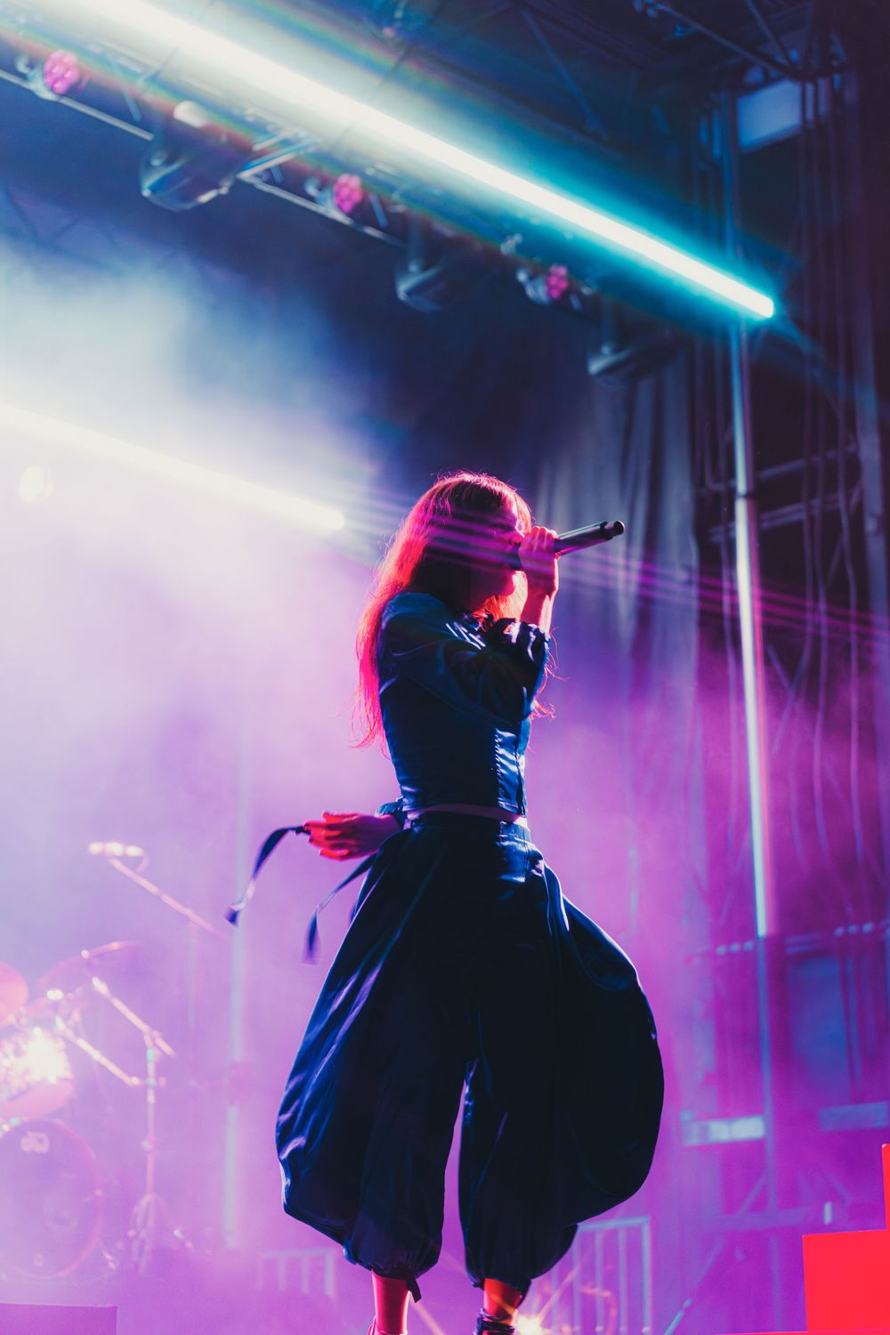 Silhouetted performer on stage with dramatic blue and pink lighting creates an atmospheric concert scene.