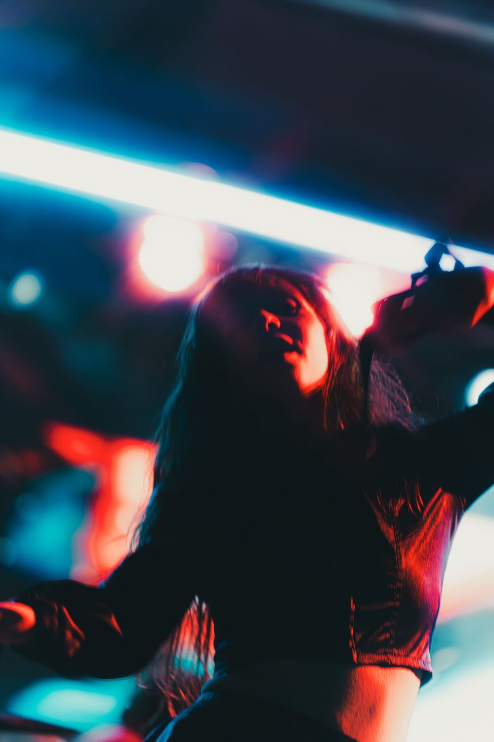 Artistic nightclub photo with neon lights showing silhouette dancing in red and blue lighting effects.