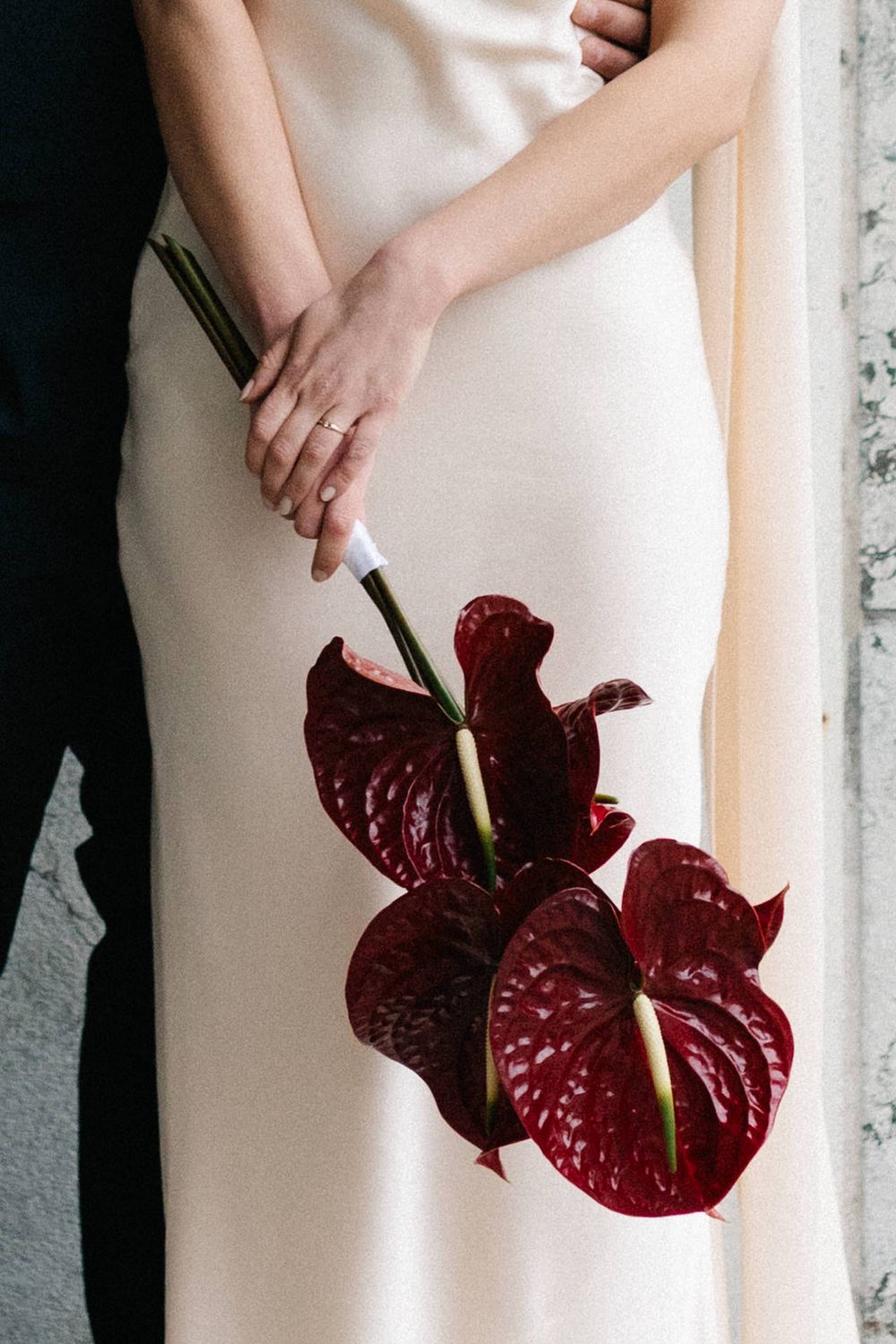 A series of photos showing deep burgundy anthurium flowers against a cream-colored dress background.
