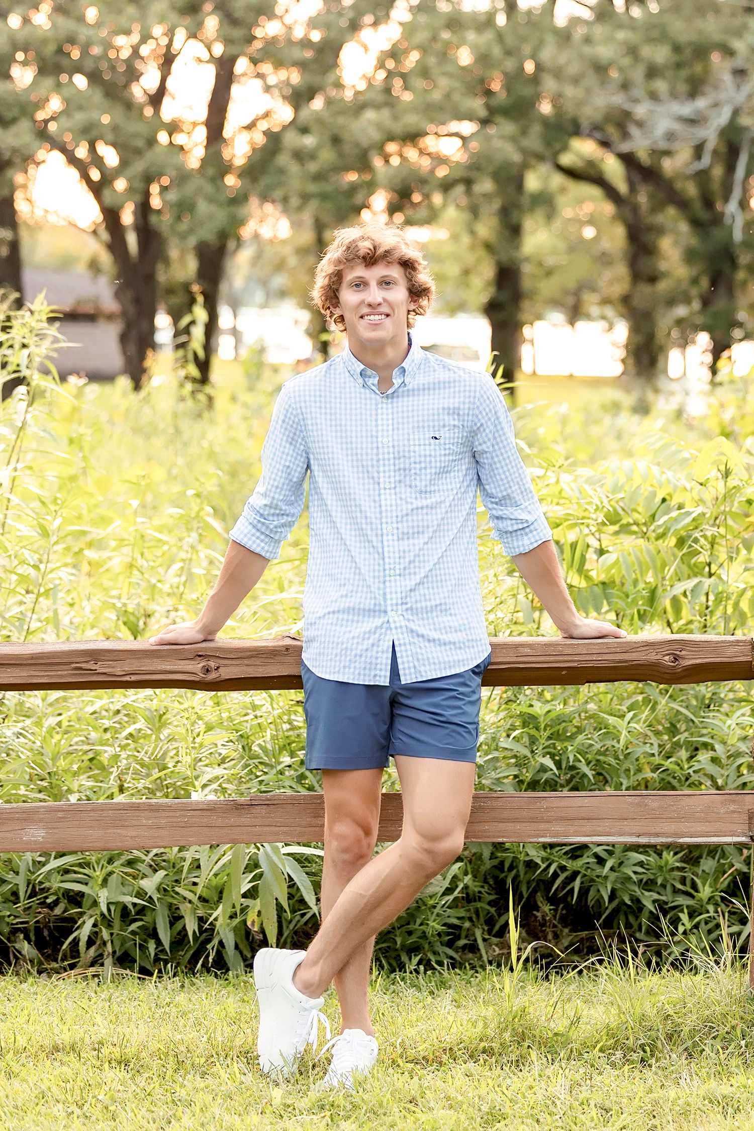 Senior boy standing by wooden fence in park during Clear Lake Iowa senior photography session