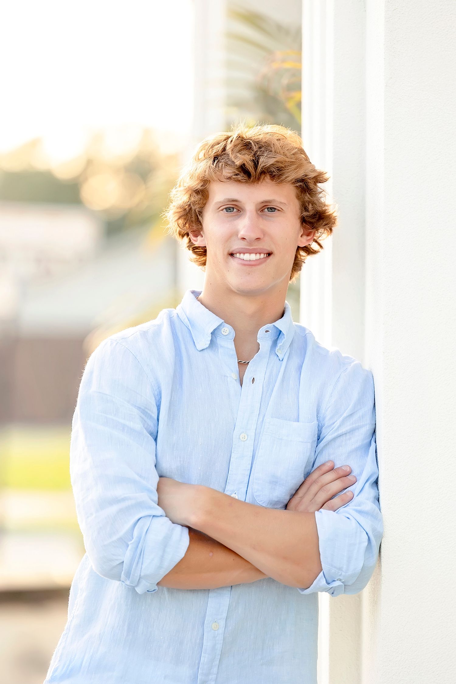 High school senior boy leaning against white columns at The Palms during downtown Clear Lake Iowa senior photos