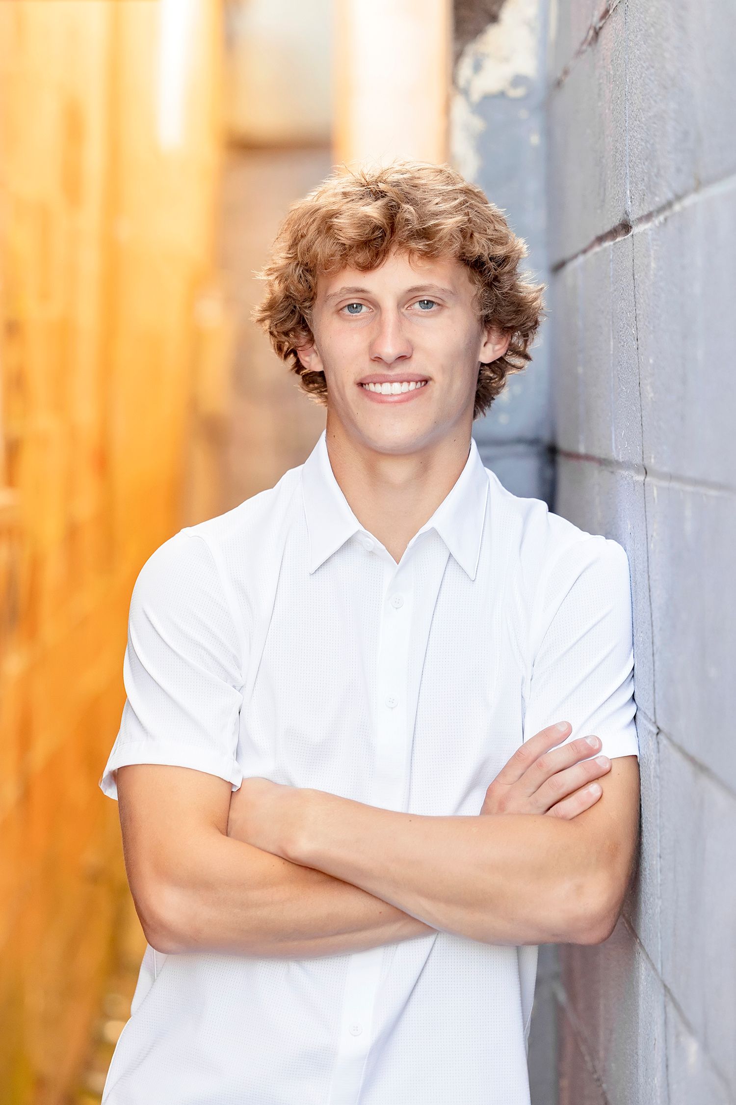 Senior boy portrait against orange wall in downtown Clear Lake Iowa senior photo session