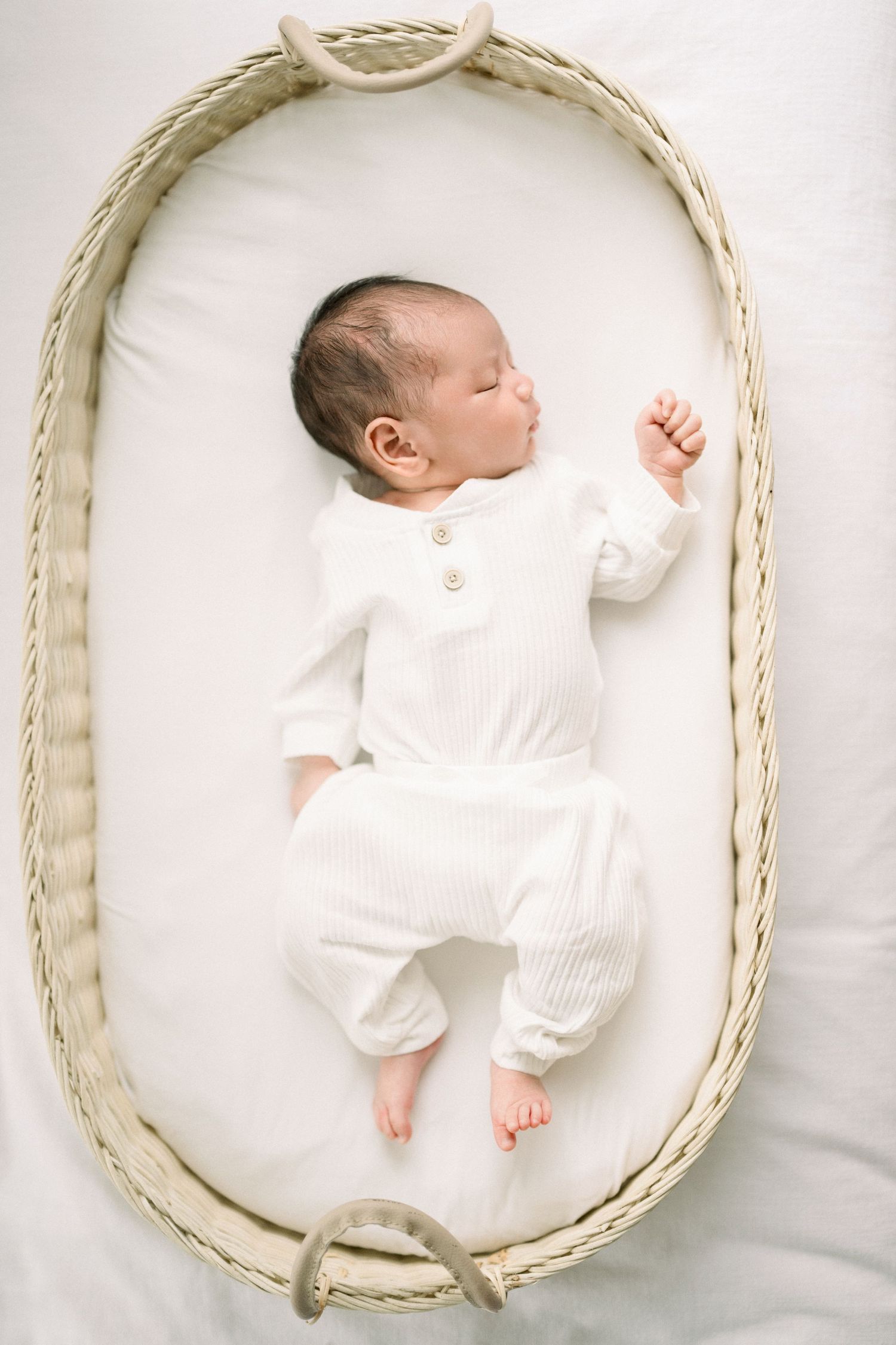 A sleeping newborn wearing white taken by a dc newborn photographer in washington dc
