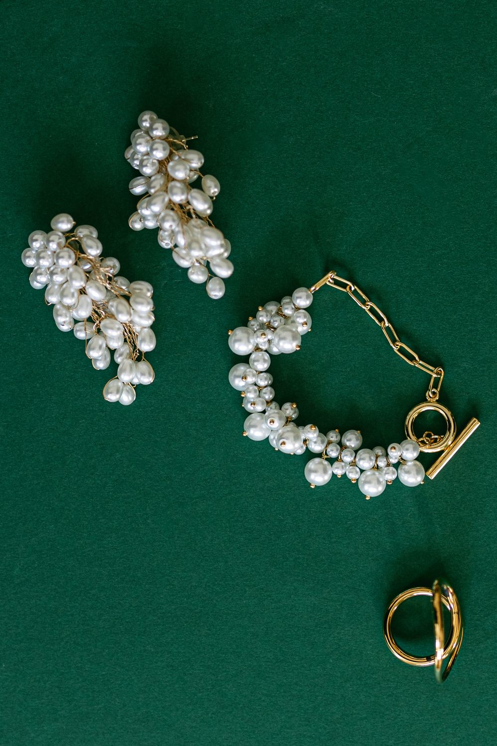 Pearl jewelry arranged on a dark green velvet background showing elegant bridal accessories.