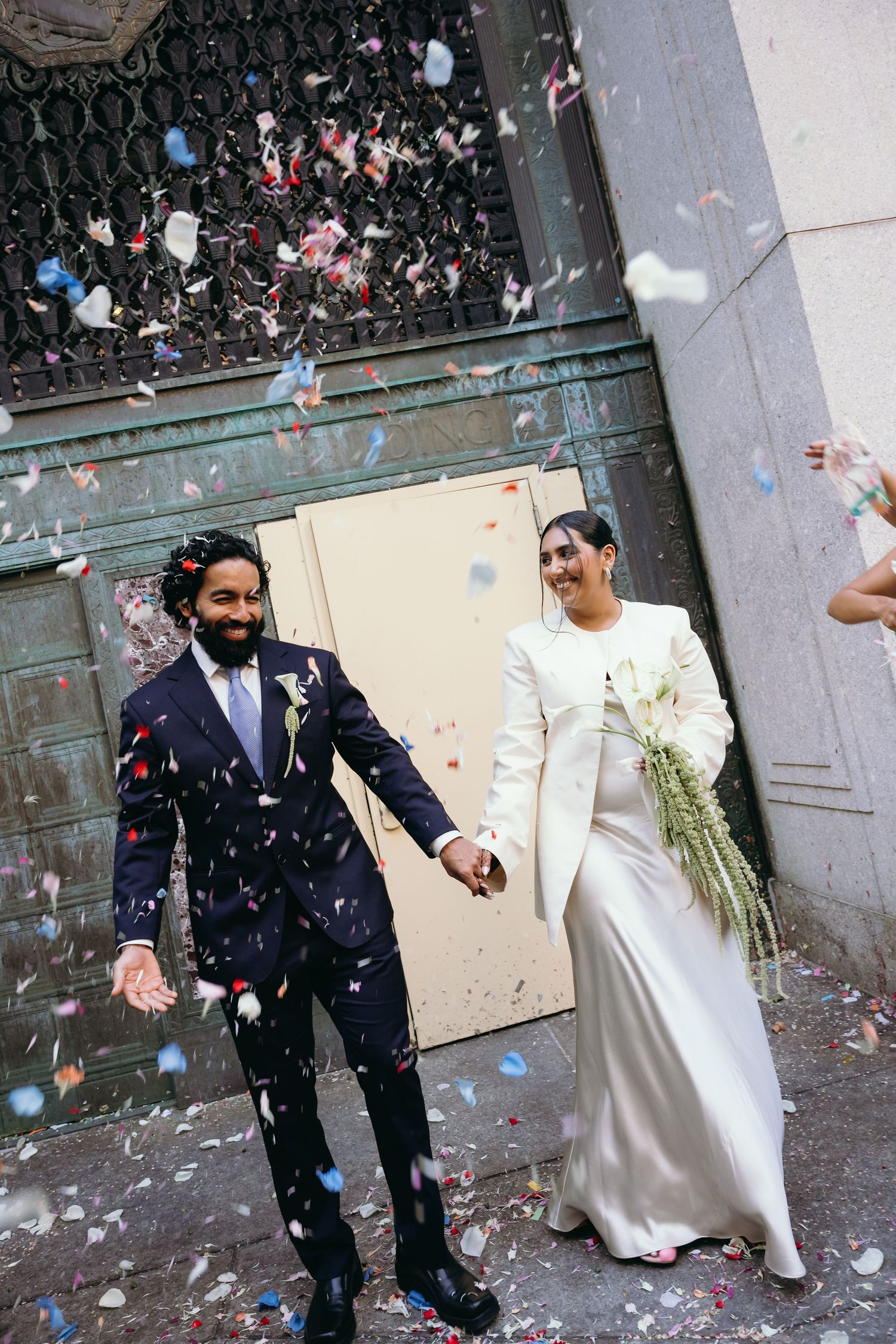 A wedding celebration with confetti falling as the couple walks through a stone corridor.