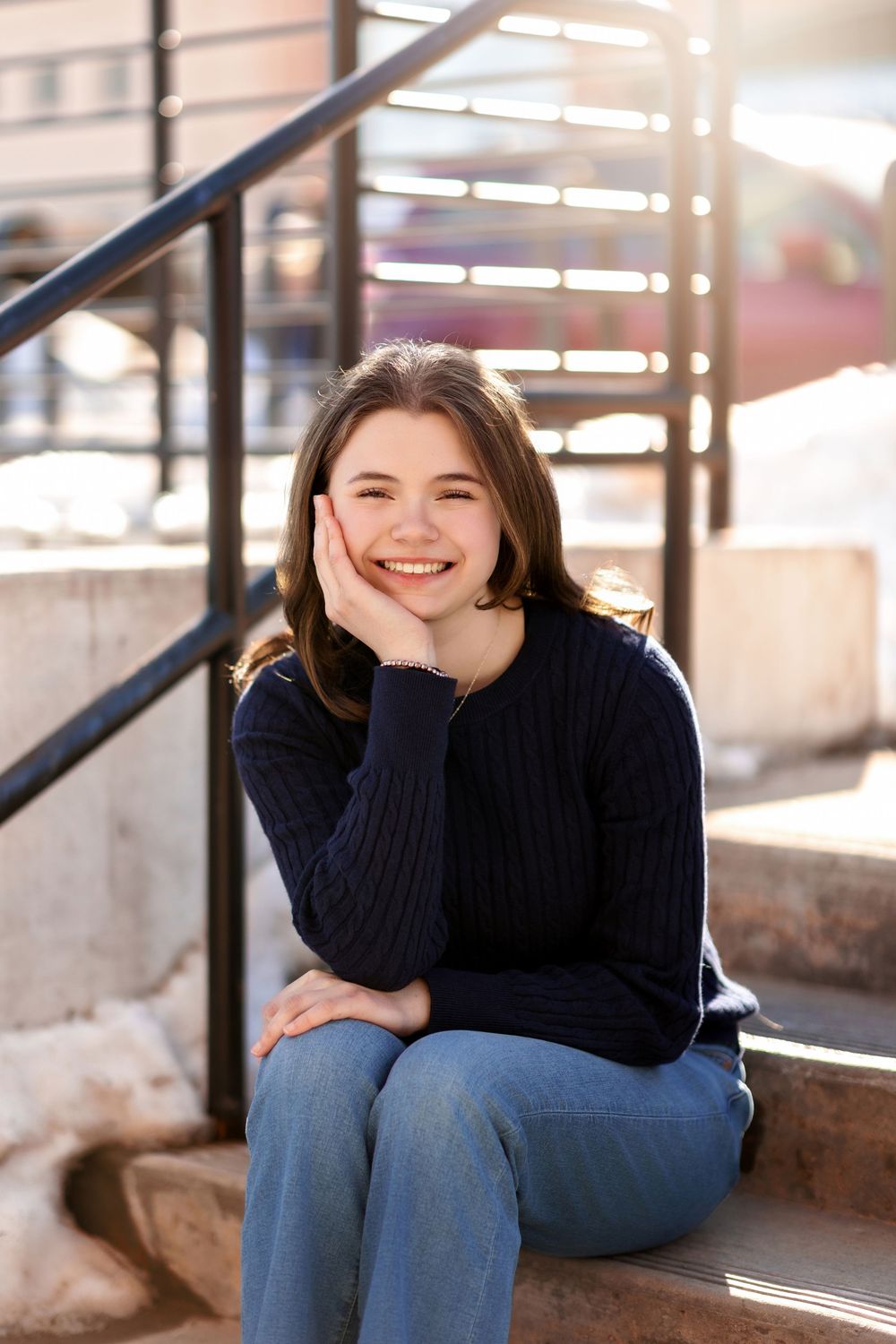 Senior girl smiling on outdoor steps during downtown Concord NH senior portrait session.