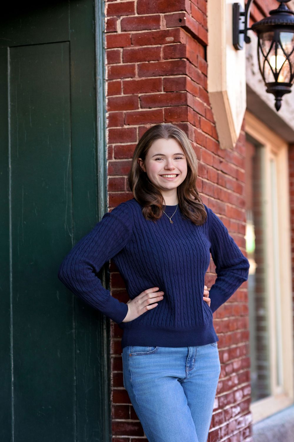 Senior girl portrait by green door and brick wall in downtown Concord NH.