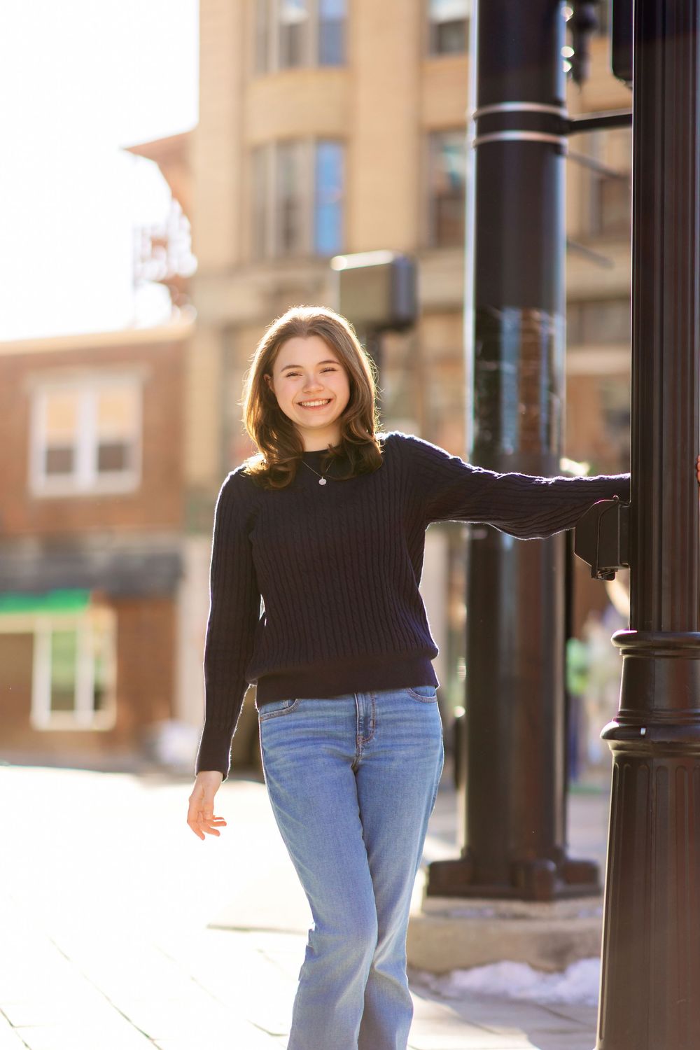 Senior walking along street with lamp post in downtown Concord NH golden light senior portrait.