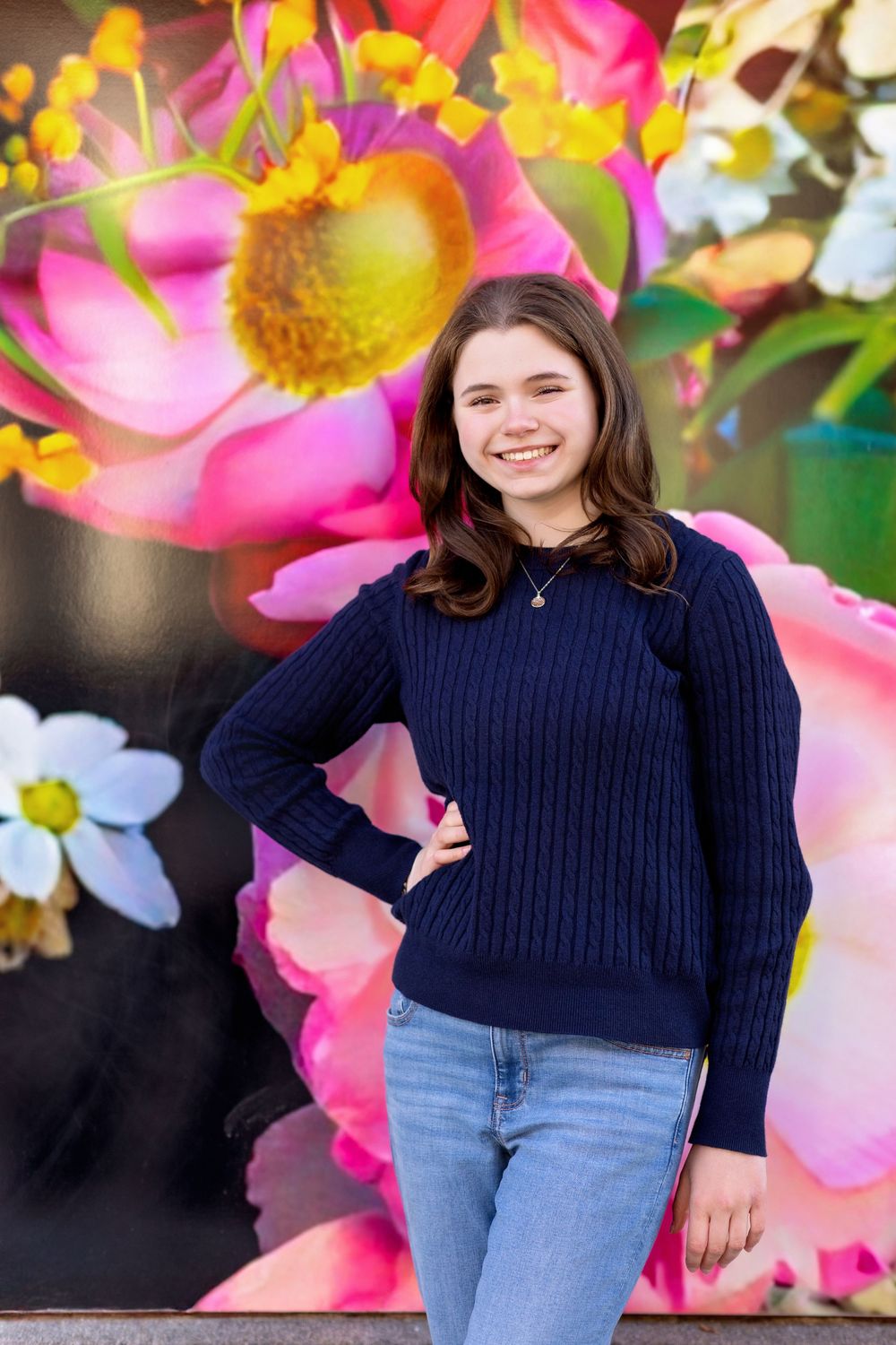 Senior girl smiling in front of bright floral mural in downtown Concord NH portrait.