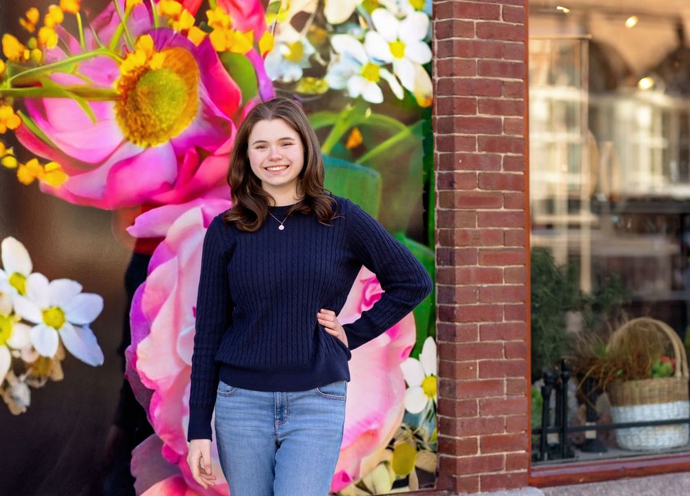 Senior portrait in front of colorful flower mural in downtown Concord NH.