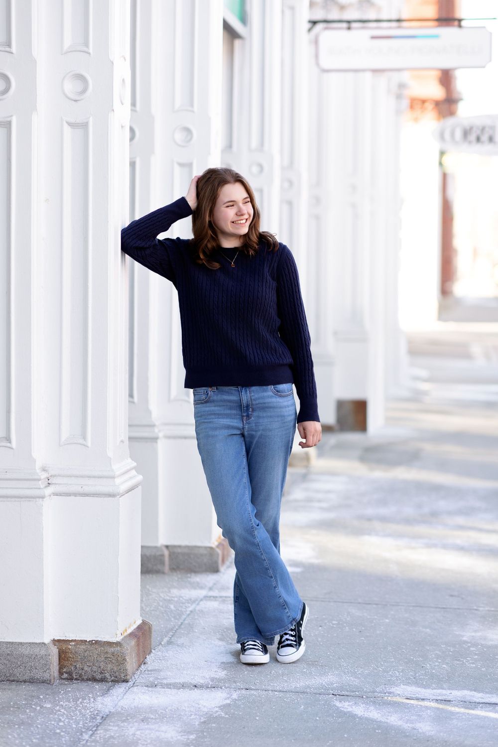 Senior girl posing beside white columns in downtown Concord NH classic architecture portrait.