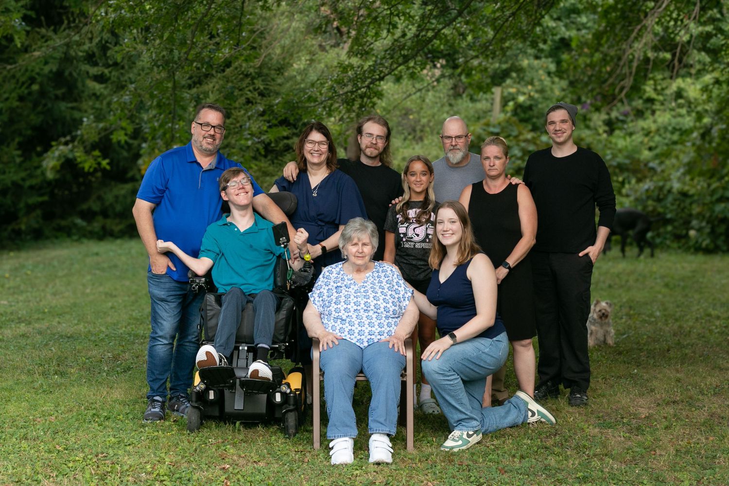 A group of people sitting together outdoors on a grassy area for a casual family photo session.