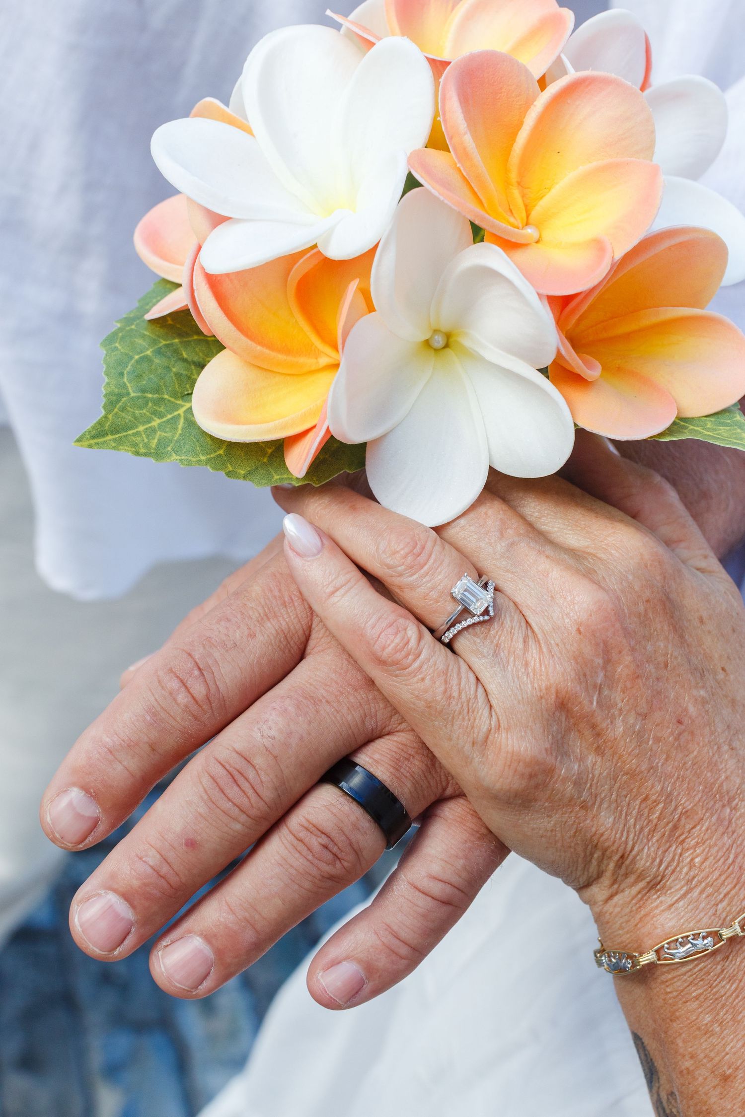 Bridal bouquet with the rings and hands of the bride and groom.