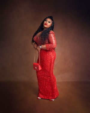 Glamorous portrait in sparkly red sequin dress against brown studio backdrop.
