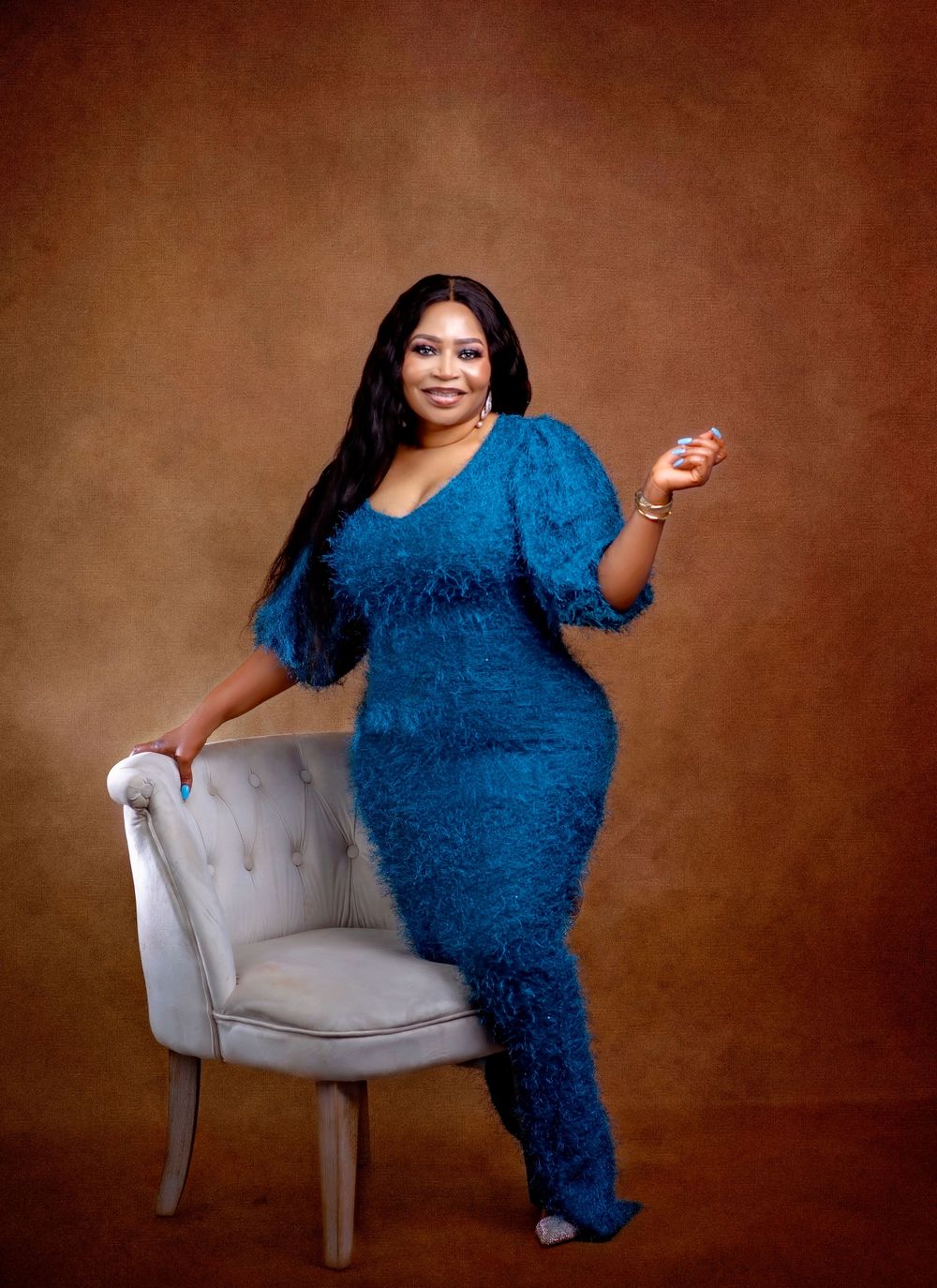 Studio portraits featuring textured royal blue dress and light gray chair.