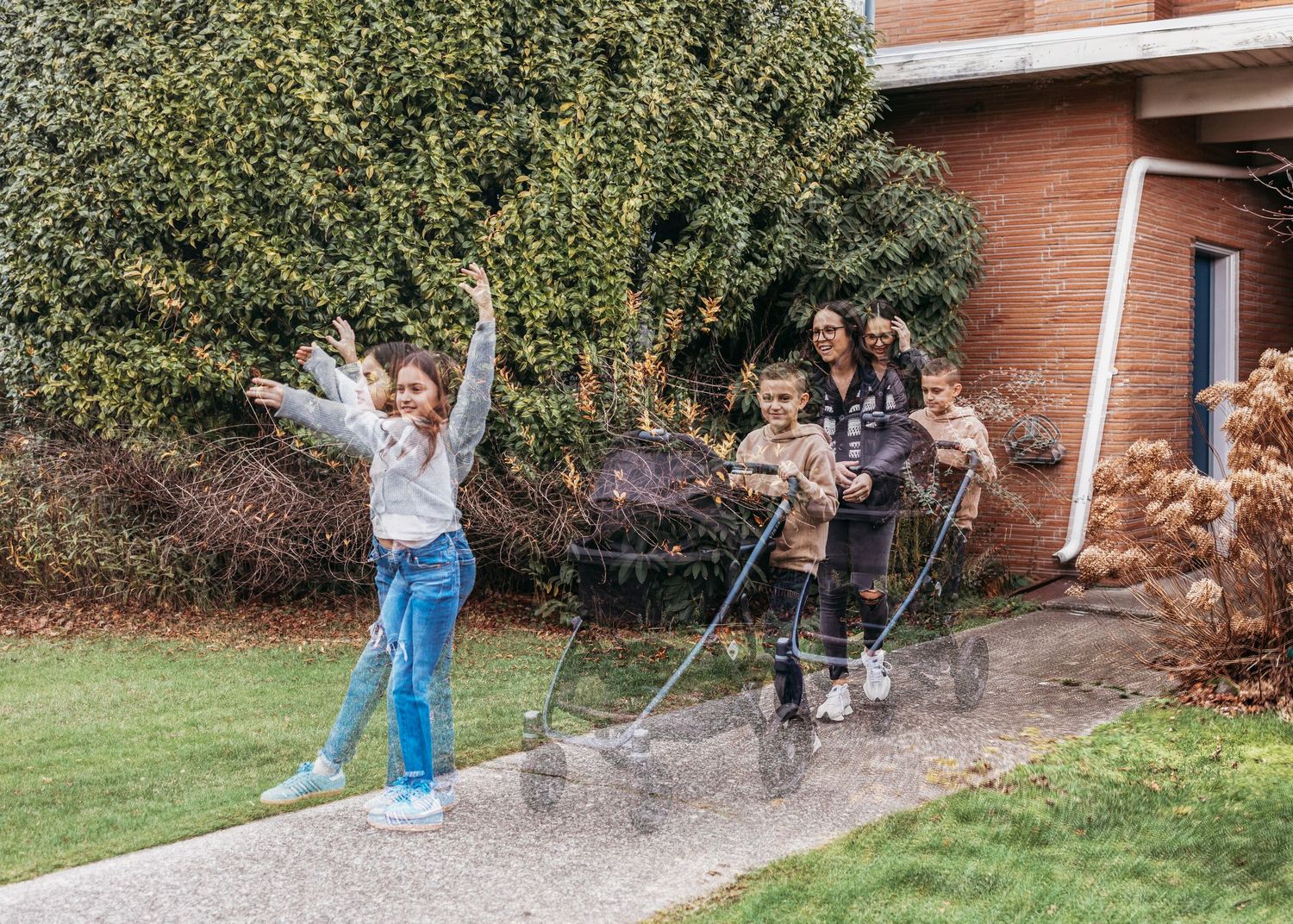 A person splashing in a large puddle on a driveway while others watch from the background.
