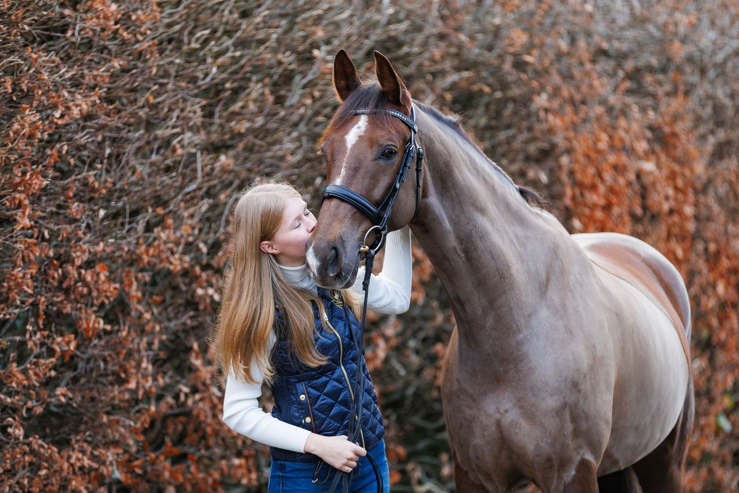 A horse and its rider enjoy an outdoor photoshoot session near rustic wooden fencing on a sunny day.