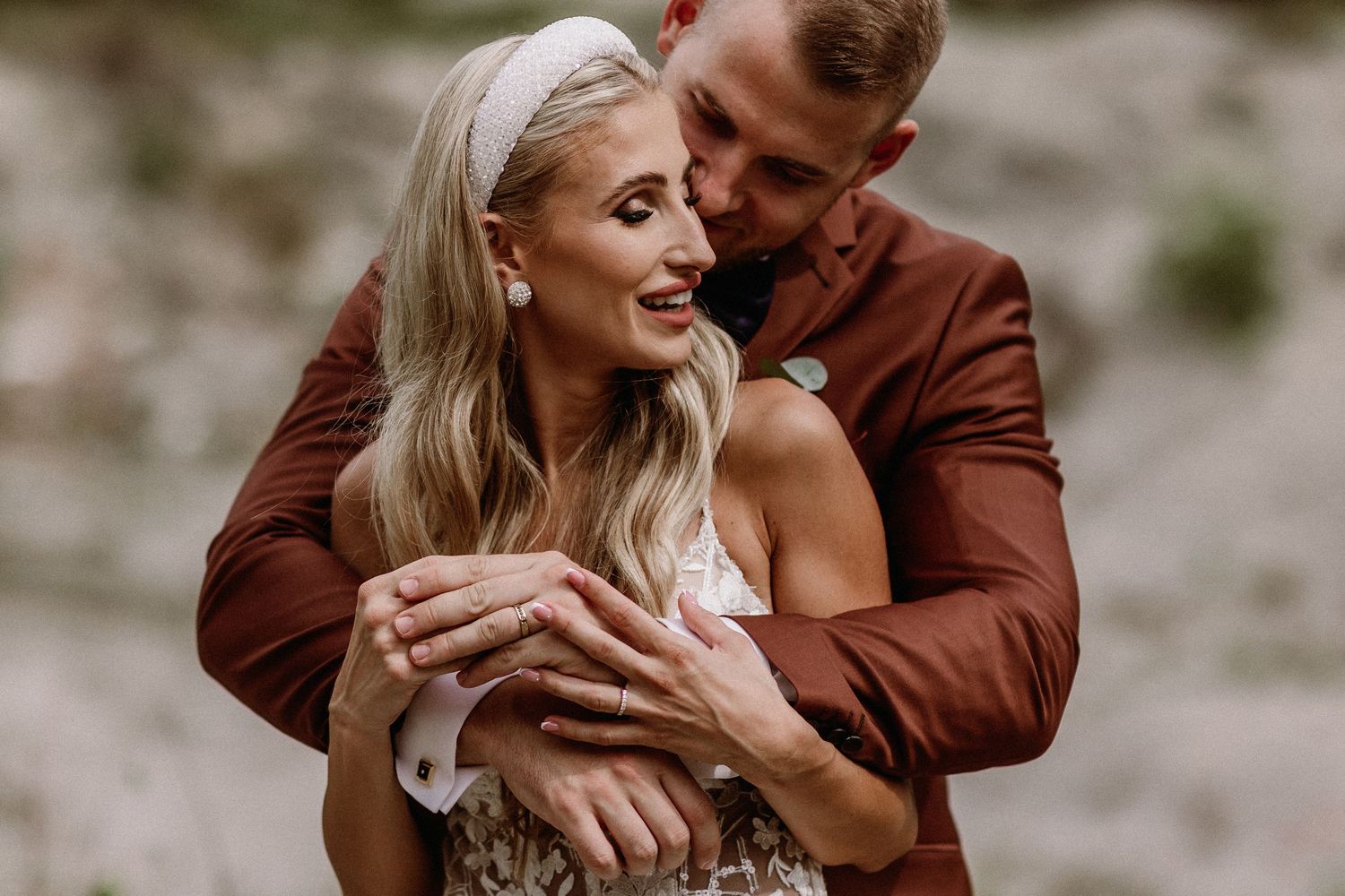 Romantický svadobný portrét v prírode – ženích v bordovom obleku objíma blonďavú nevestu. Svadba v Žiline – Erika a Peter.