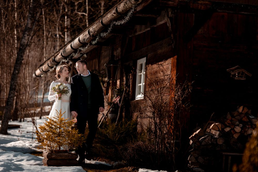 Romantisches Paar vor historischer Schwarzwald-Hütte im Henslerhof. Authentische Winterhochzeit in Hinterzarten.