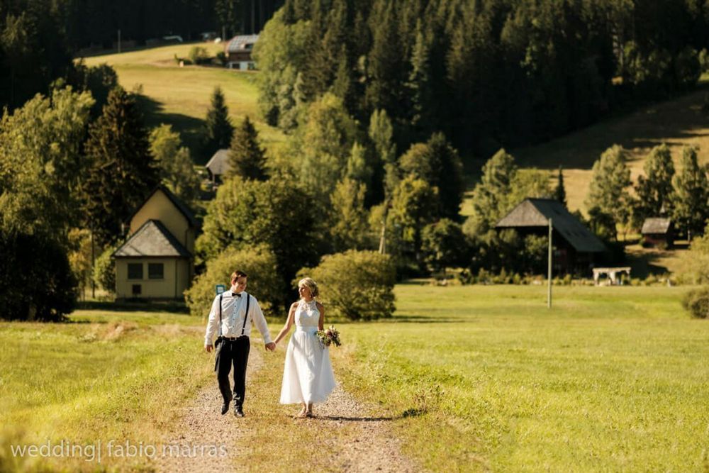 Sommerhochzeit im Schwarzwald. Ein Paar spaziert über die Wiesen am Henslerhof, Hinterzarten