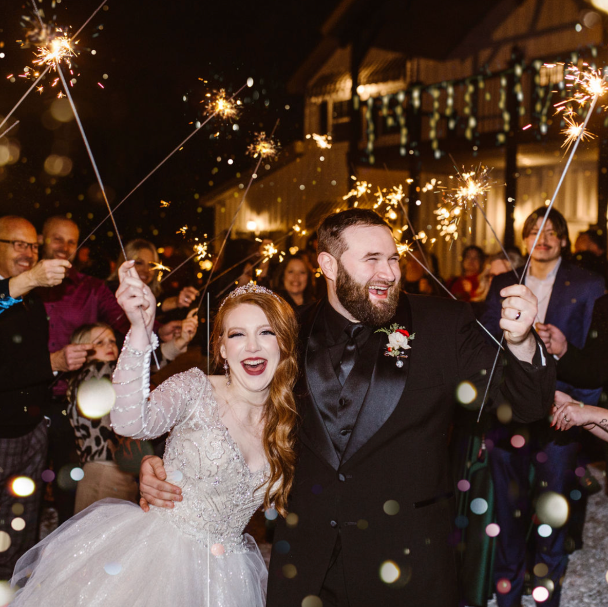 A joyful celebration at night with sparklers and twinkling lights creating a magical wedding atmosphere.