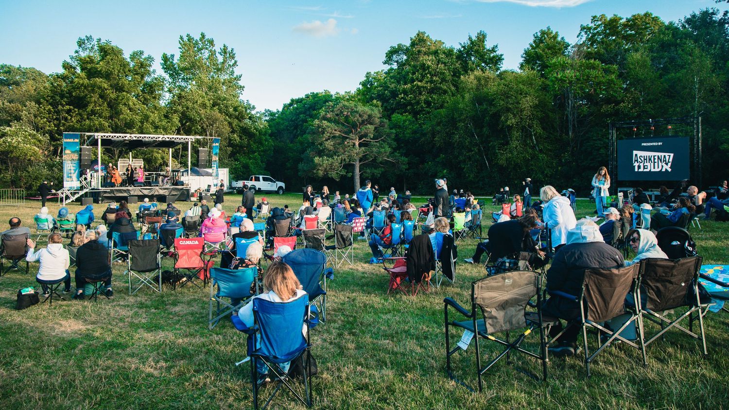 People gather at an outdoor festival with tents and activities during sunset creating a vibrant community atmosphere.