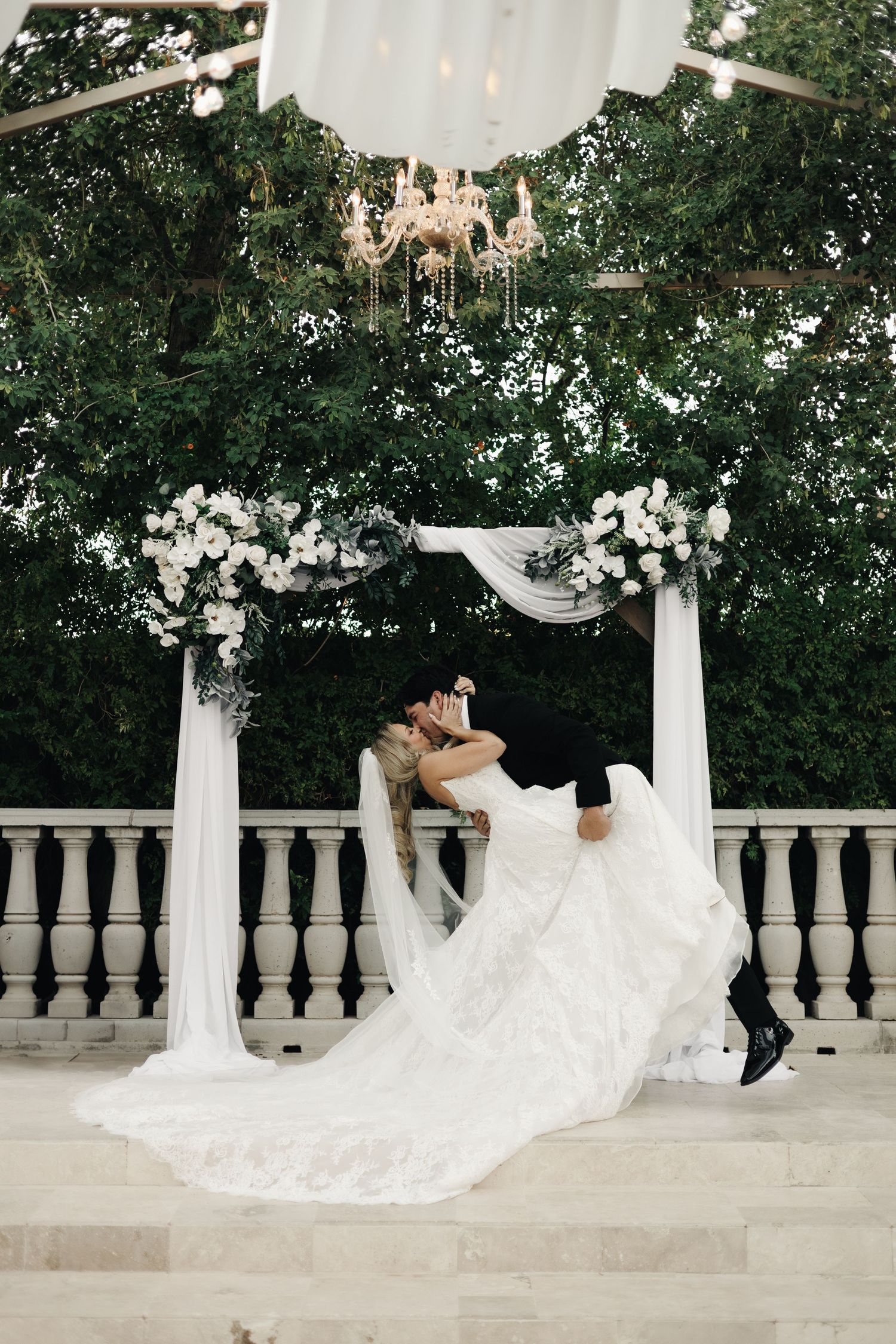 A flowing white wedding dress twirls gracefully against a backdrop of tall cypress trees at sunset.
