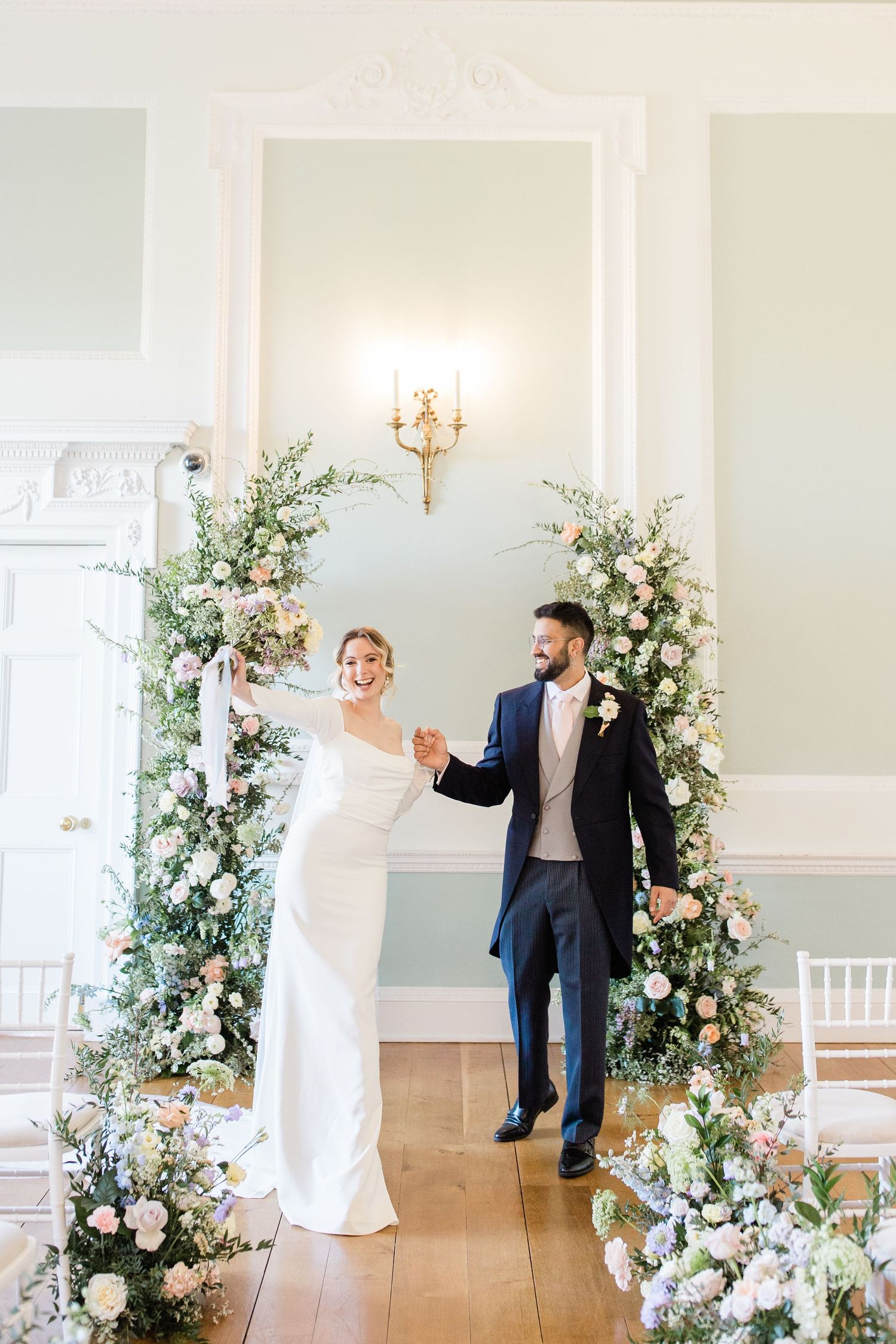 A wedding celebration sequence showing a couple dancing and celebrating in an elegant white room with floral arrangements.
