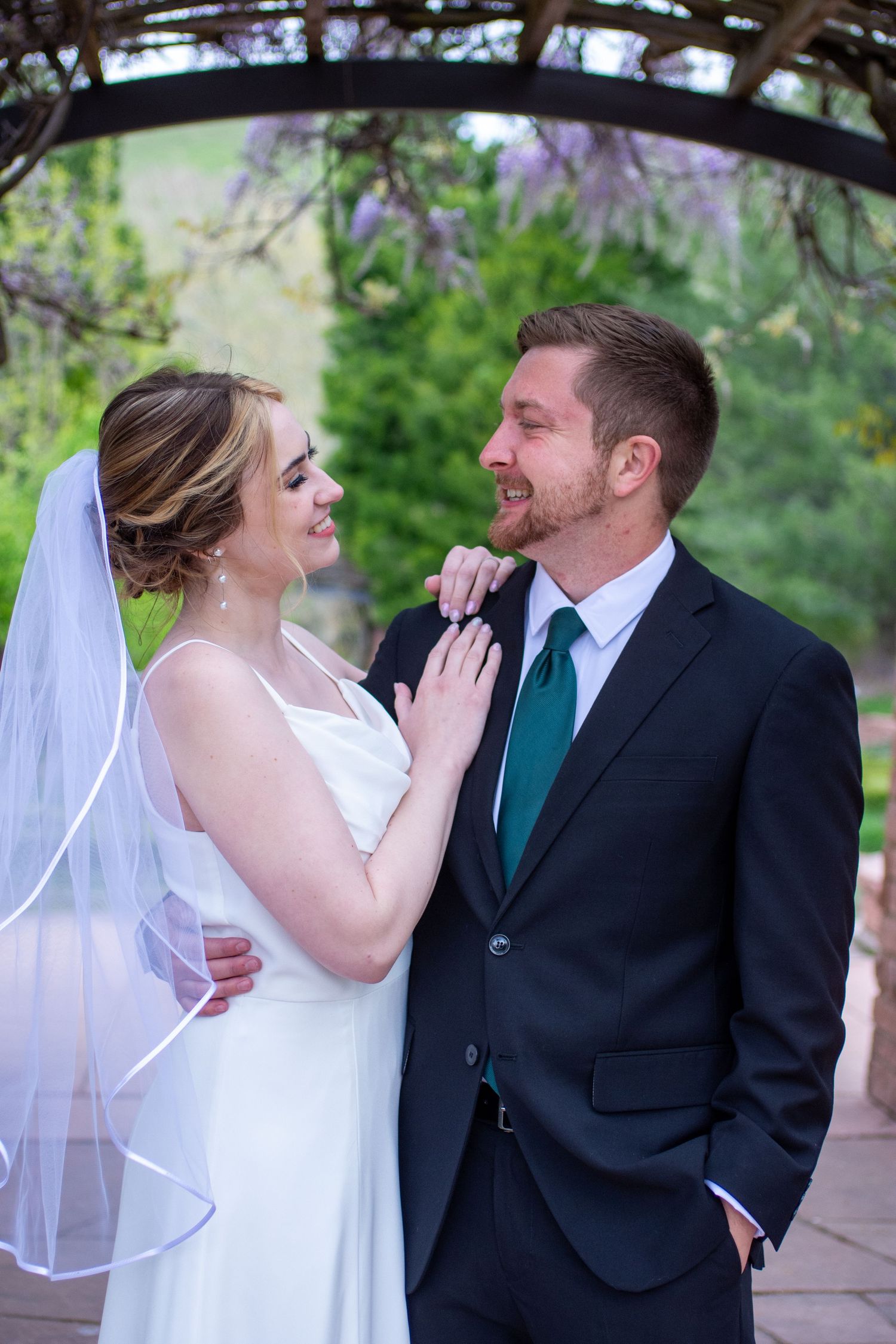 A couple in wedding attire share a romantic moment together in a garden setting.