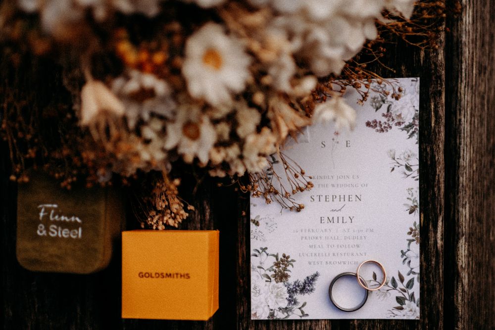 Wedding invitation suite with floral designs and elegant calligraphy displayed on a rustic wooden surface.