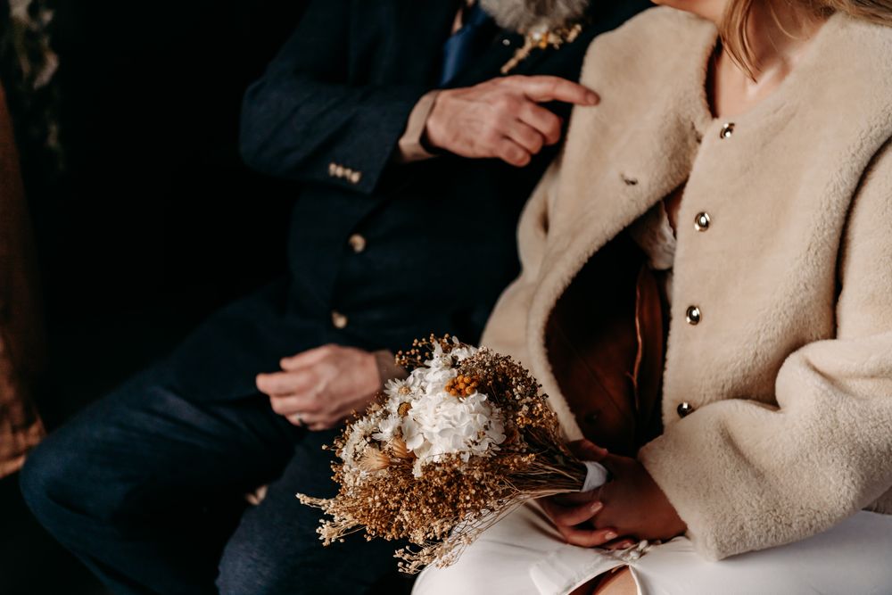 People in cozy beige sweaters holding warm drinks and enjoying conversation together in a dimly lit setting.