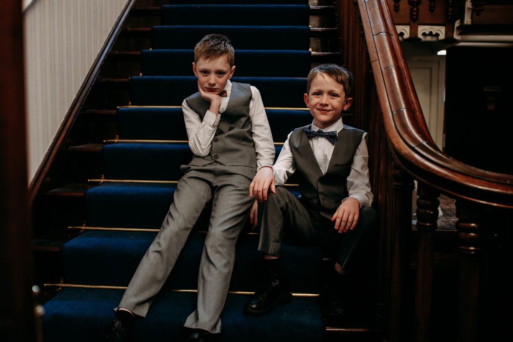 A group of people in formal attire pose together on a staircase during a wedding celebration.