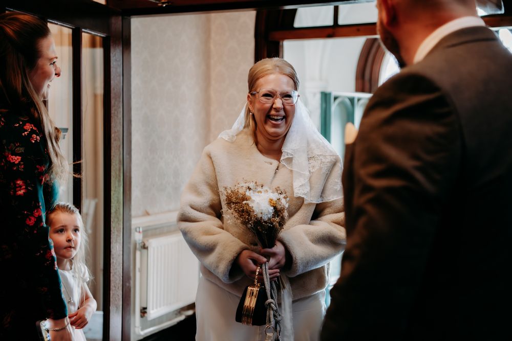 A joyful moment captured during a wedding ceremony as attendees gather near a doorway.