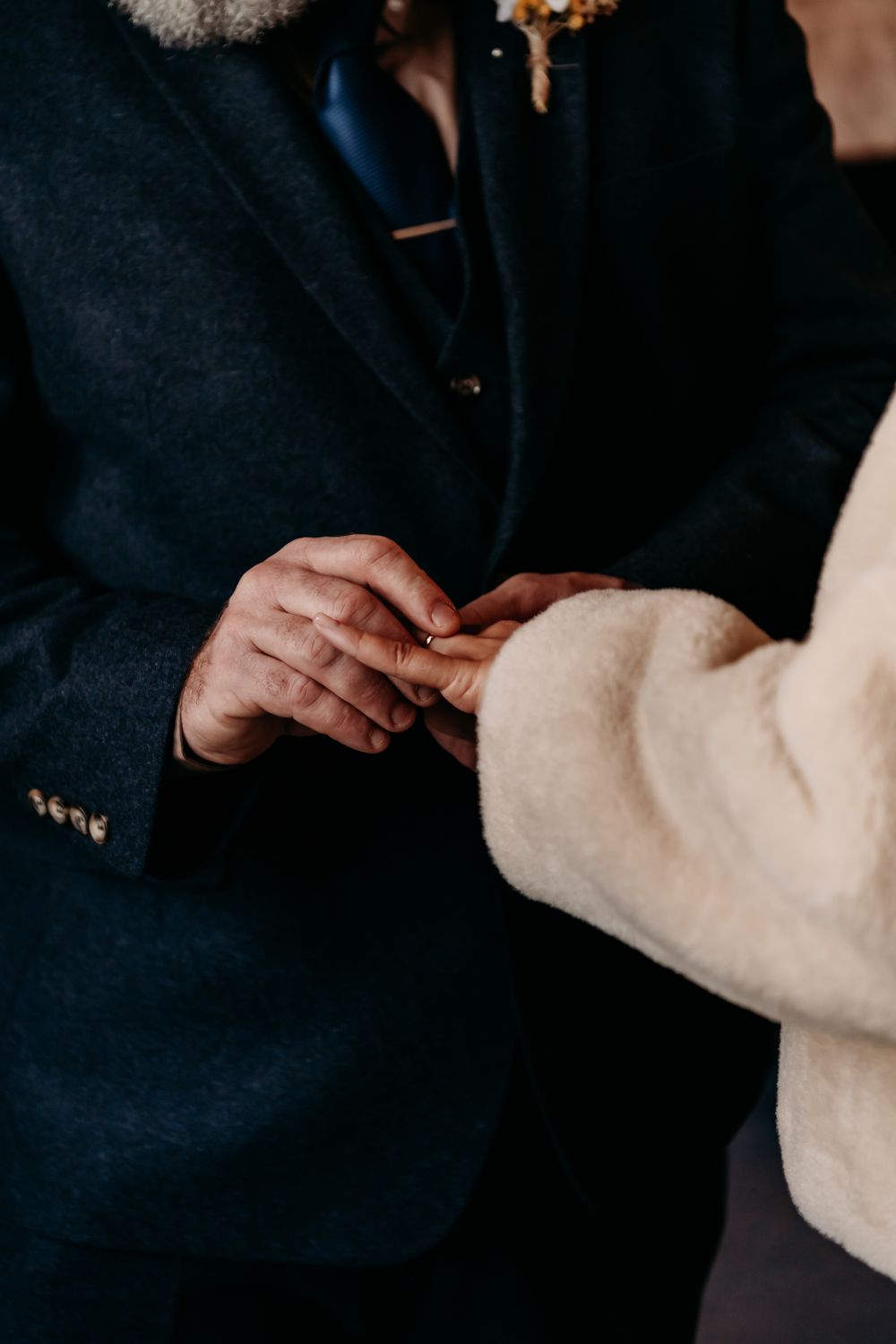 Close-up view of hands adjusting a white fluffy pillow against a dark background.