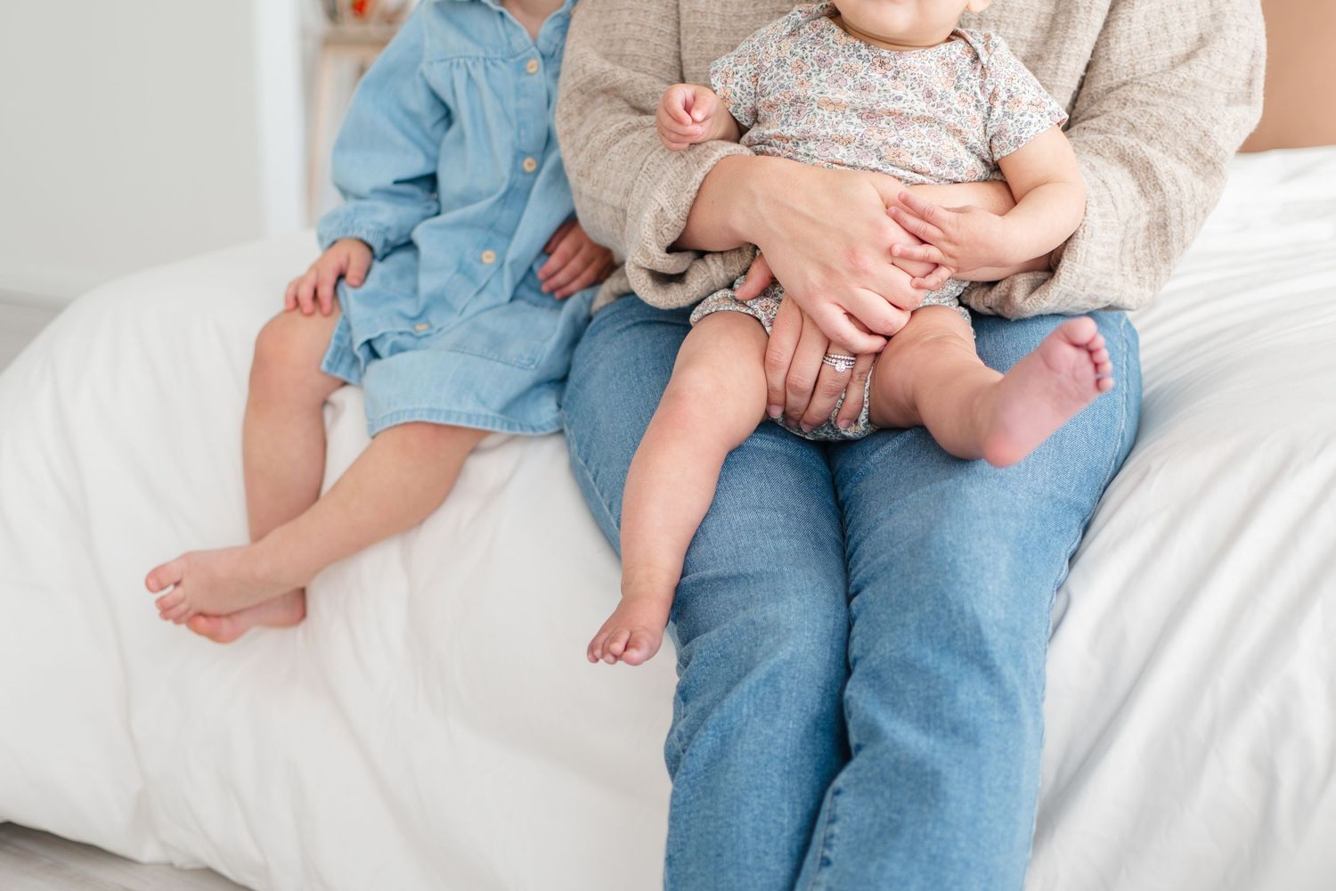 Children sitting together on white couch wearing casual clothes.