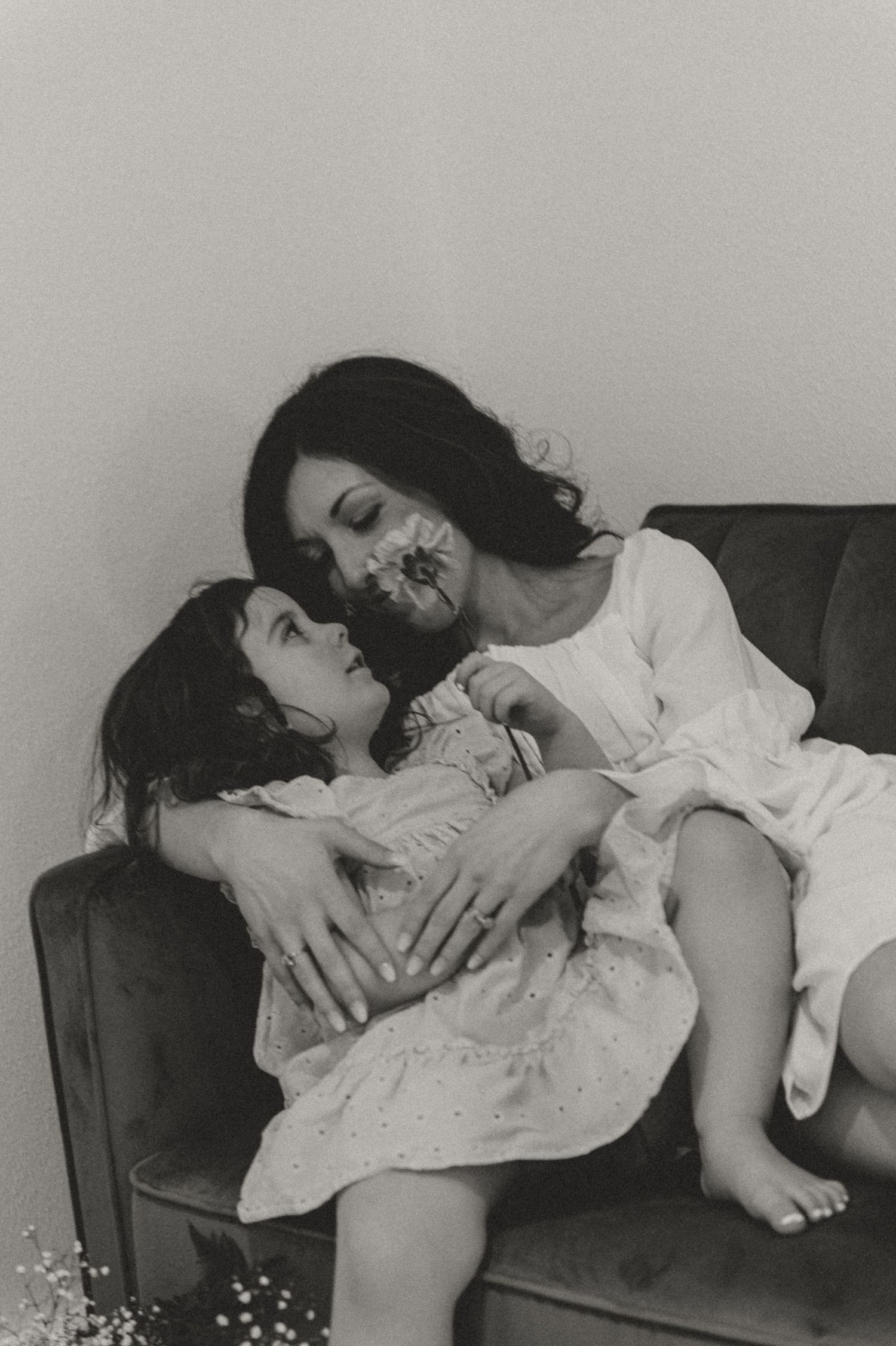 A tender black and white portrait of a mother and child sharing an intimate moment on a couch.