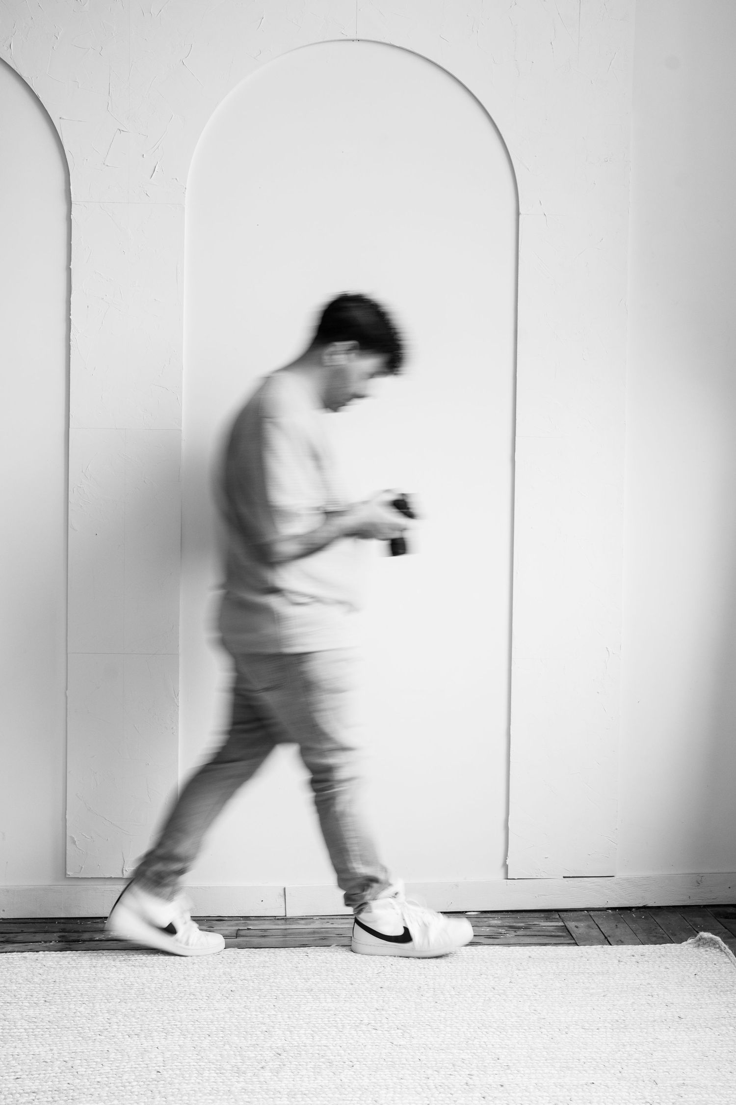 Artistic black and white photo of person walking through arched doorway.
