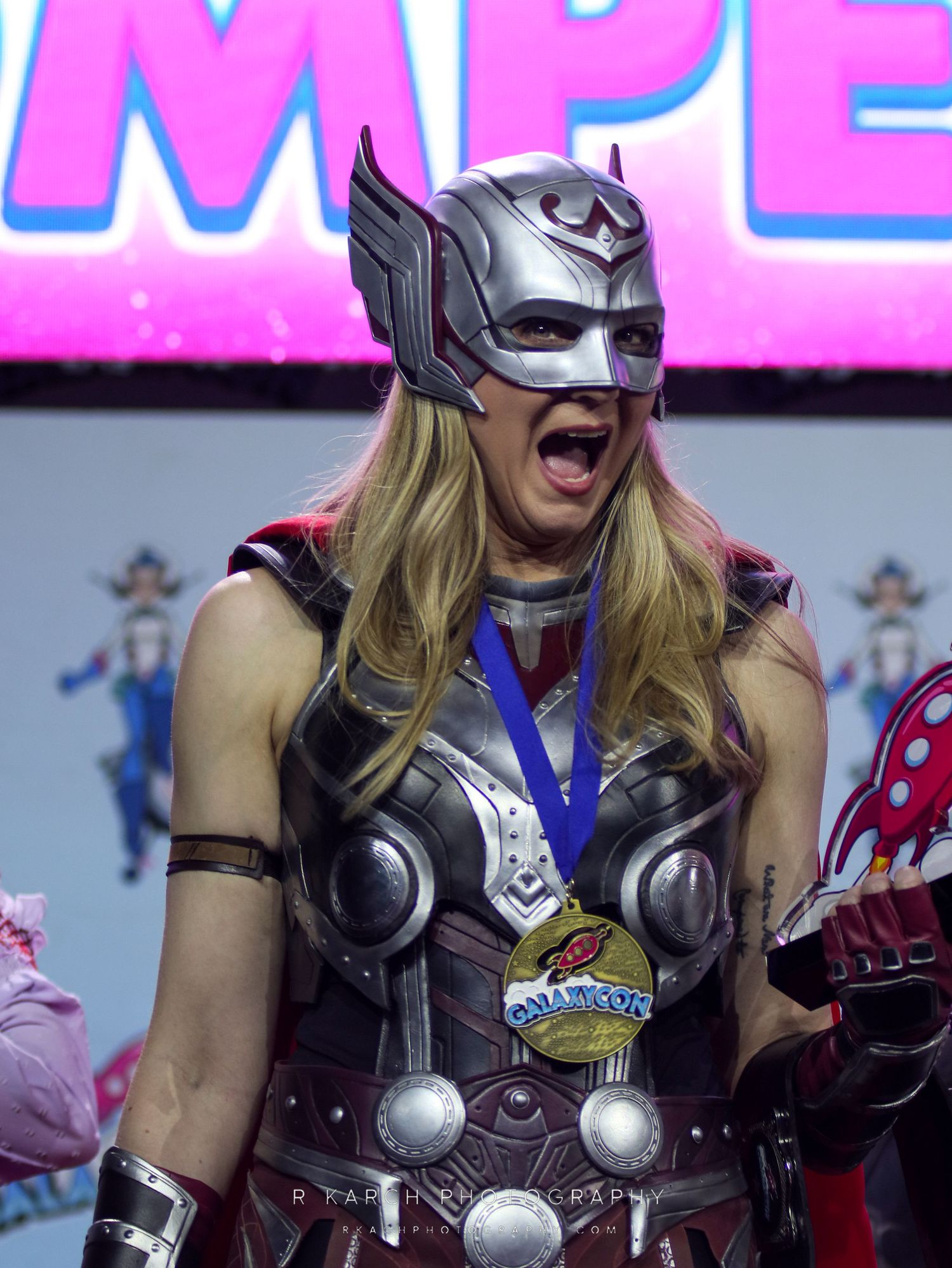 Cosplayer in Thor-inspired armor and winged helmet at a convention.