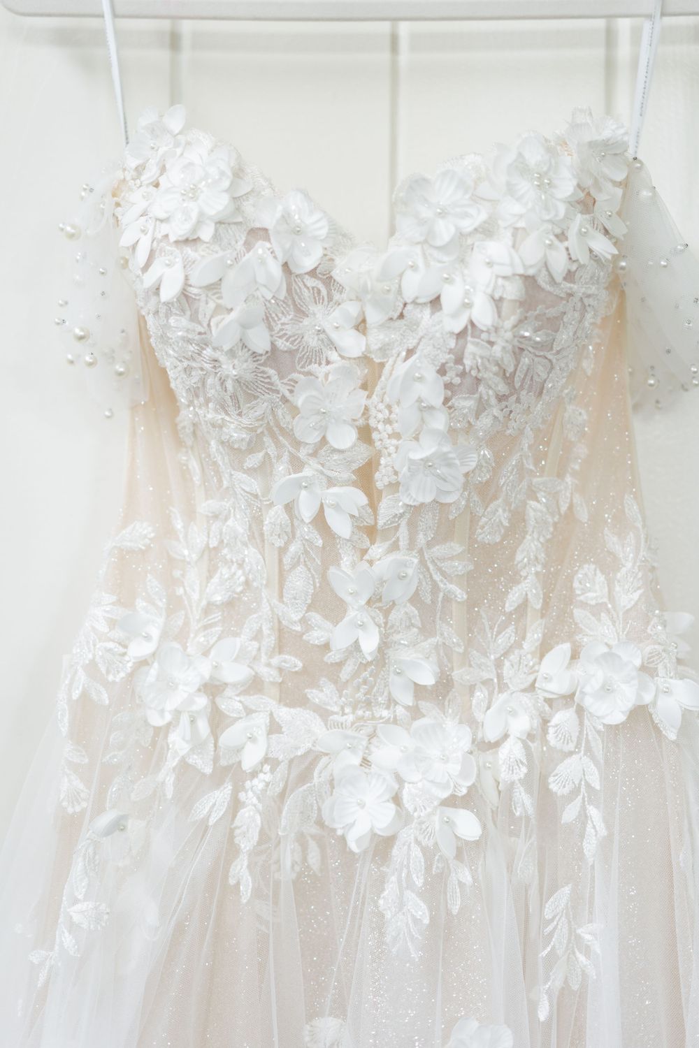 Delicate floral lace detailing on the bodice of a white wedding gown.