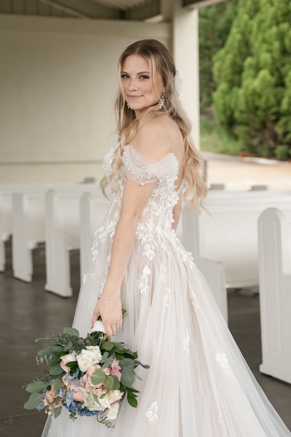 A bridal portrait showcasing an off-shoulder lace wedding gown with a flowing train.