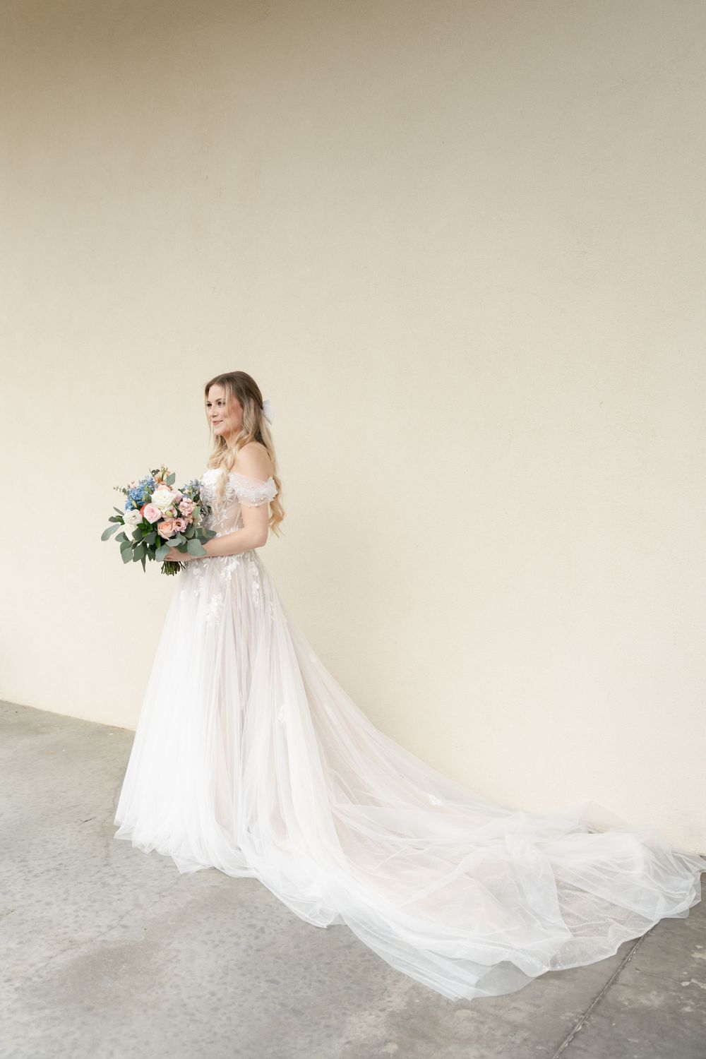 Full-length bridal portrait showing the dramatic train of a white lace wedding gown.
