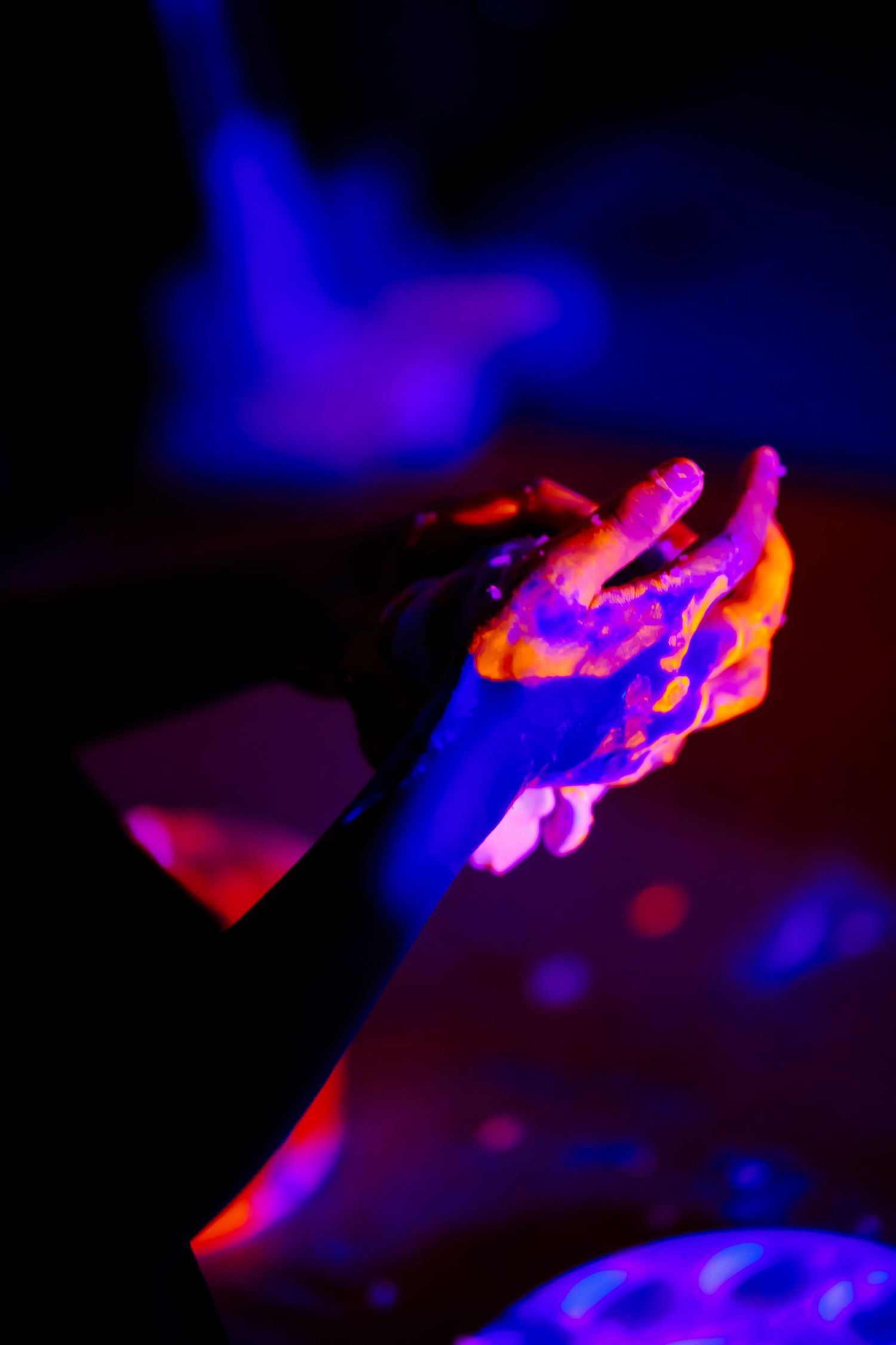 Hands illuminated by neon lights creating dramatic red and blue glow effect.