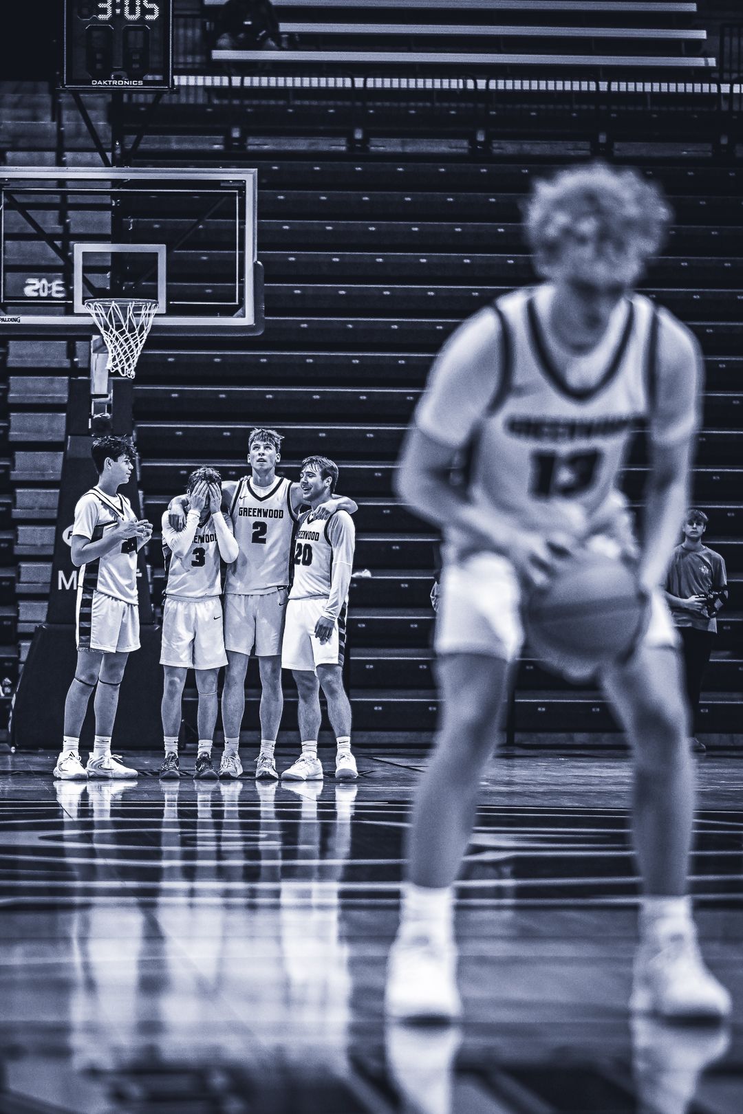 Basketball players on court in black and white with dramatic composition and lighting.