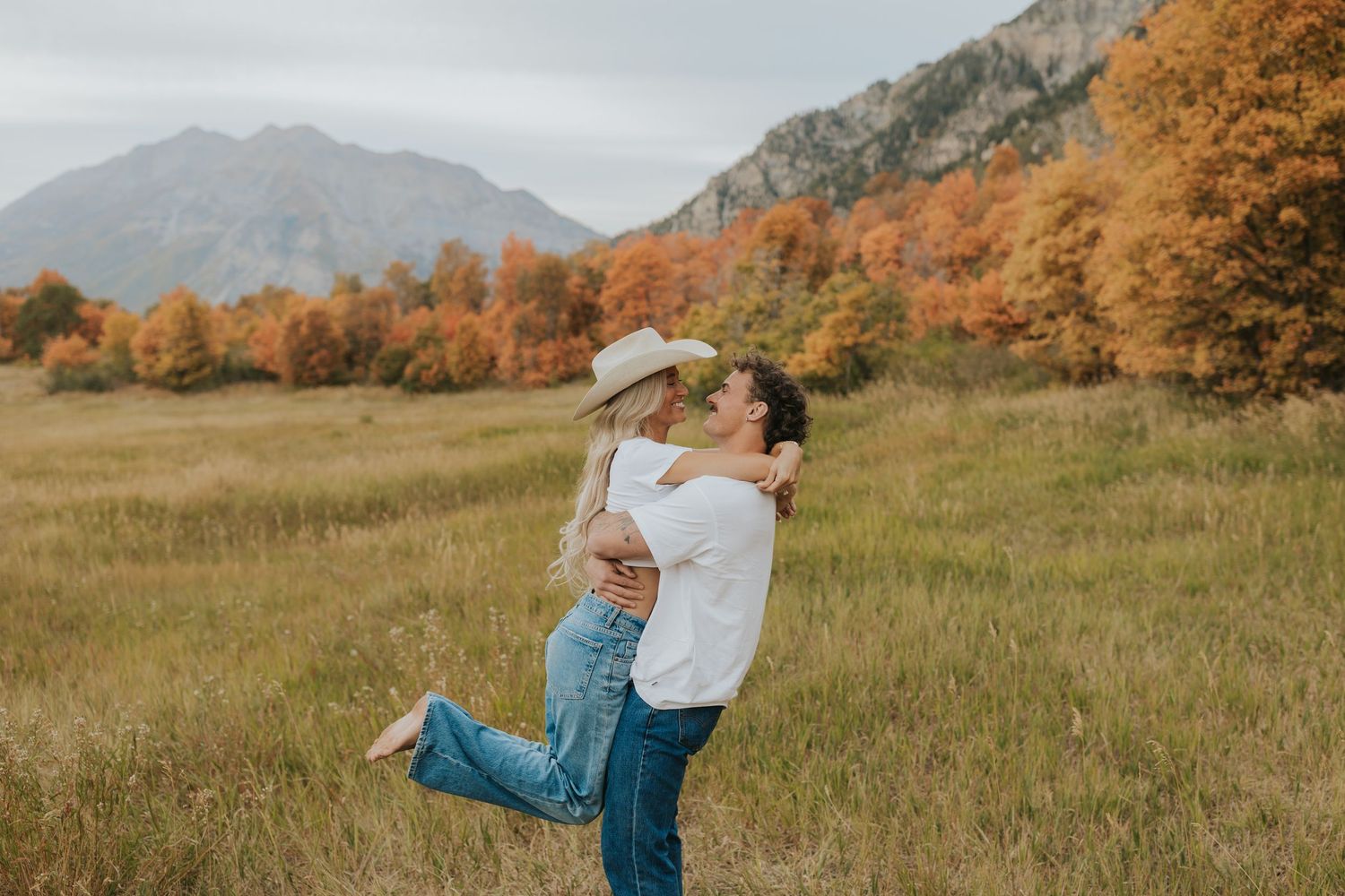 Cowboy dipping his bride in a black dress, boots, and cowboy hat, in front of cactuses on a dirt road for a western engagement session.