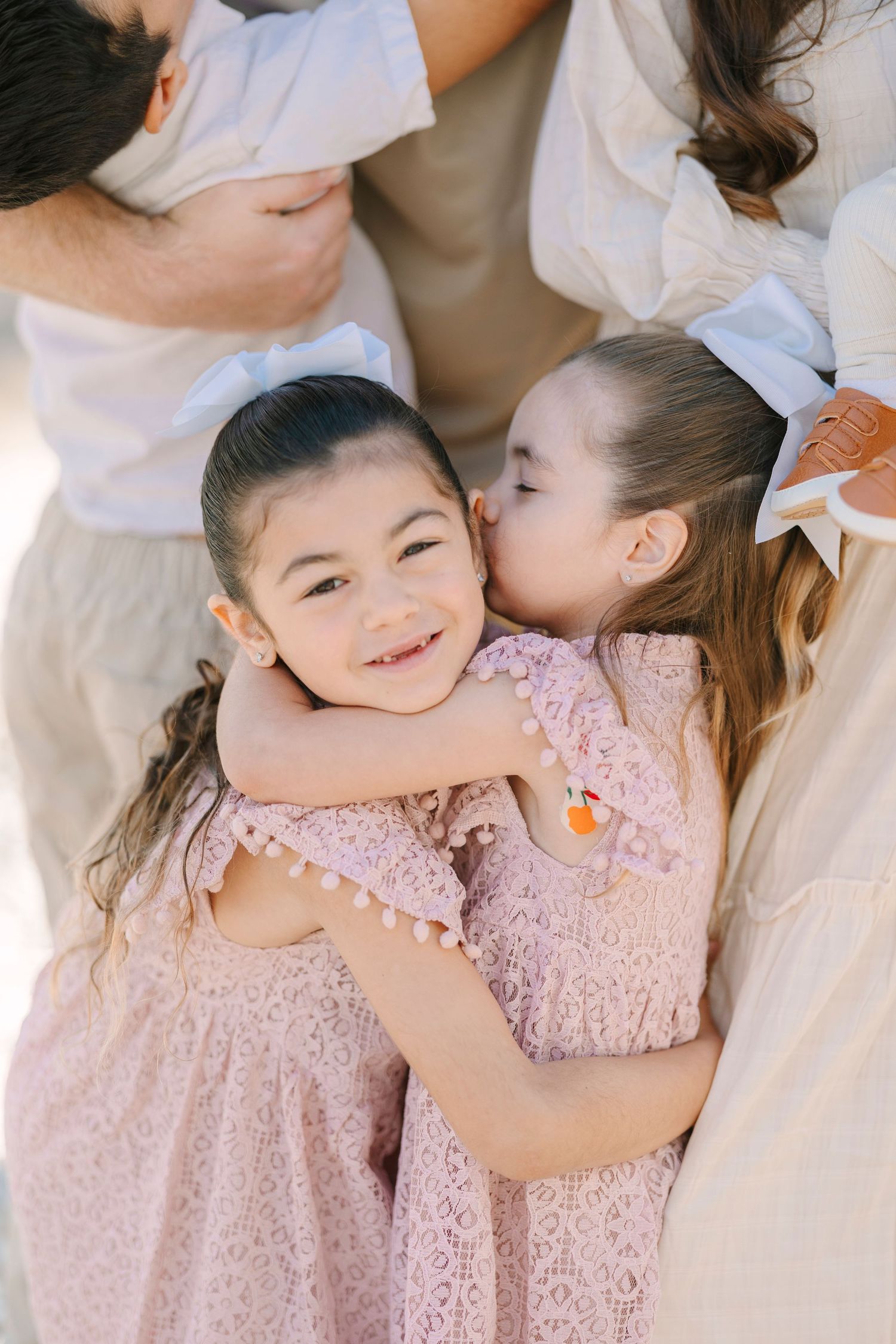 Candid moments of joy and laughter captured in soft pink tones during a family photoshoot.