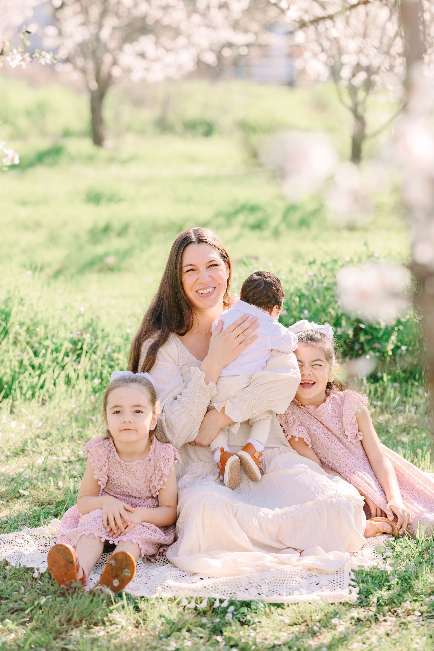 Relaxed outdoor family portrait session under blooming trees on a sunny spring day.